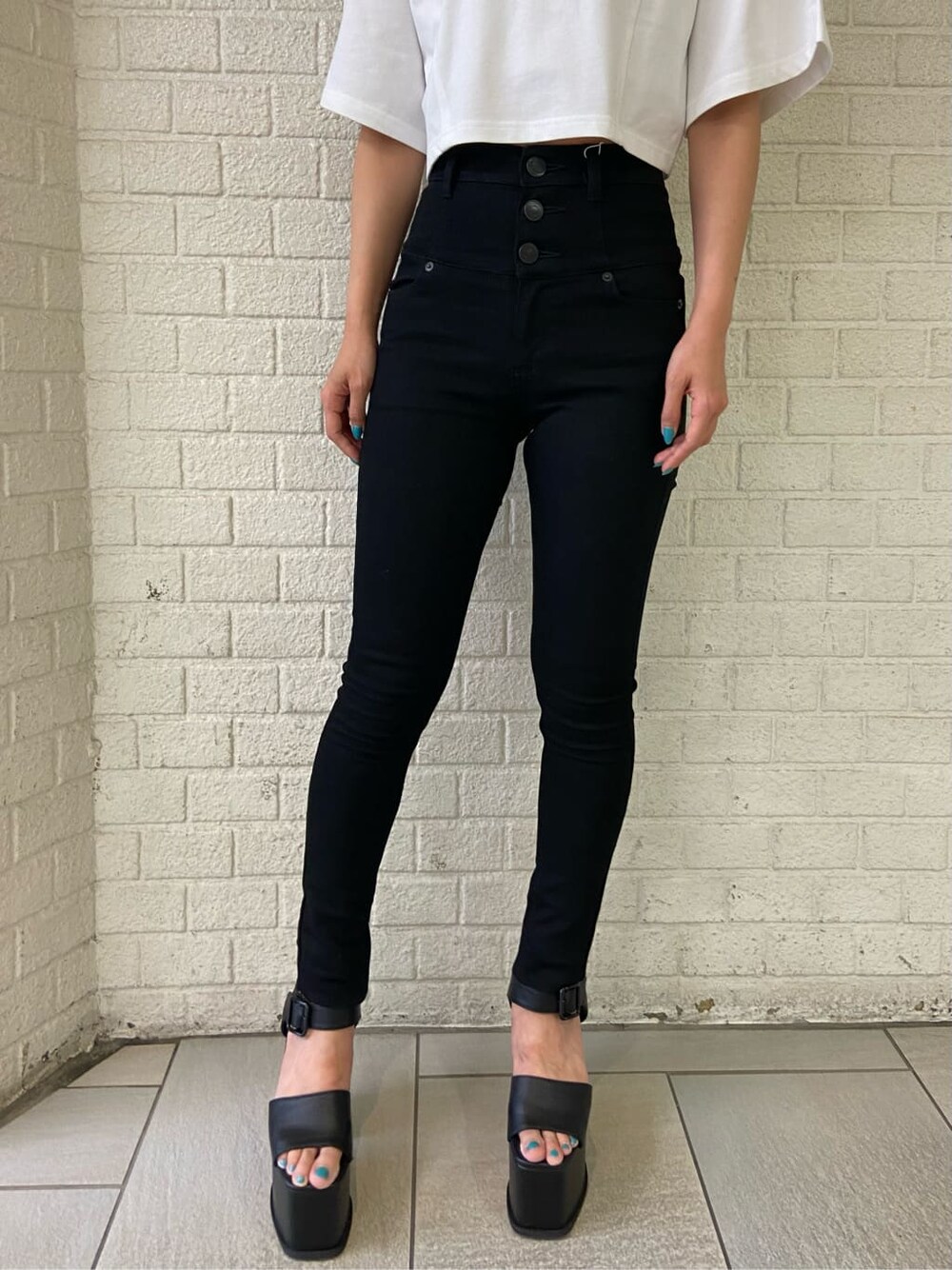 ブラック系のデニムパンツ、ブラック系のサンダル、ホワイト系のTシャツ/カットソーを着用したレディースの夏コーディネートの4枚目の写真