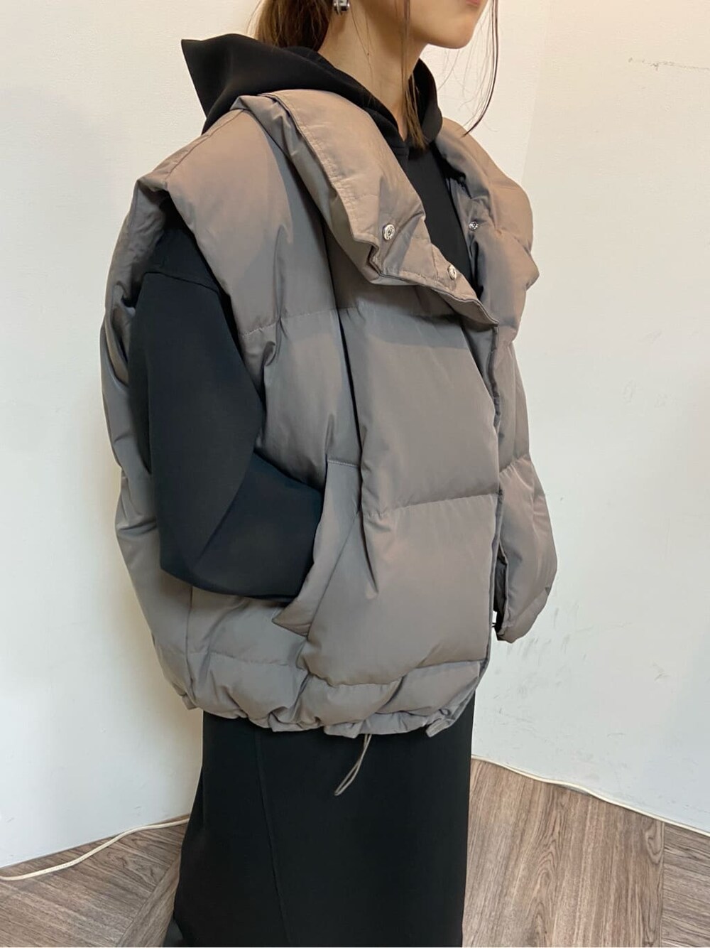 グレー系のダウンベスト、ブラック系のワンピースを着用したレディースの秋コーディネートの3枚目の写真