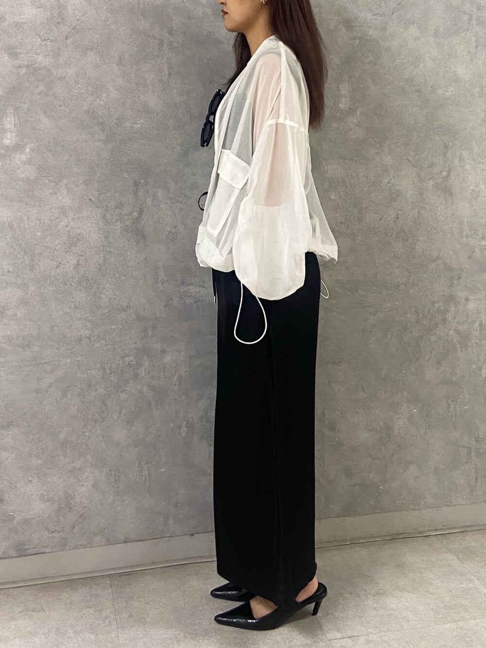 ホワイト系のブルゾン、ブラック系のタンクトップ、ブラック系のスカートを着用したレディースの春コーディネートの2枚目の写真