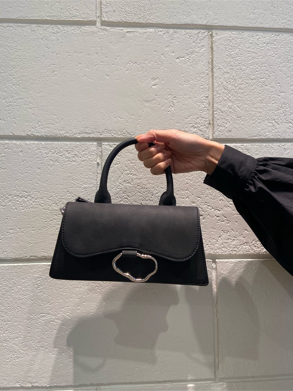 ブラック系のシャツワンピース、ブラック系のブーツ、ブラック系のハンドバッグを着用したレディースの冬コーディネートの7枚目の写真