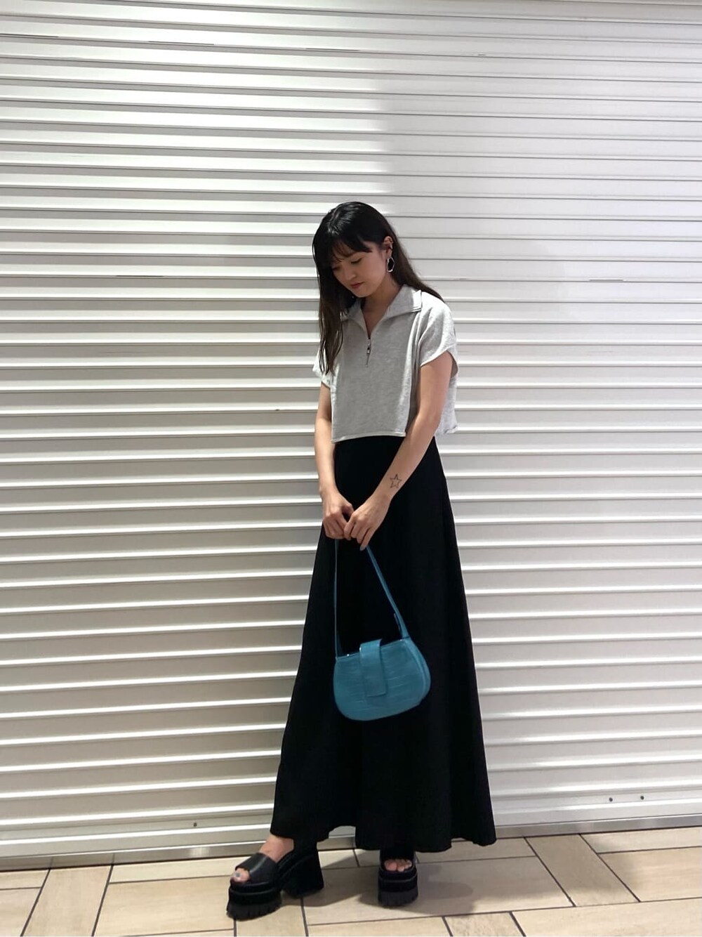 ブラック系のスカート、ブラック系のサンダル、グレー系のTシャツ/カットソーを着用したレディースの夏コーディネートの2枚目の写真