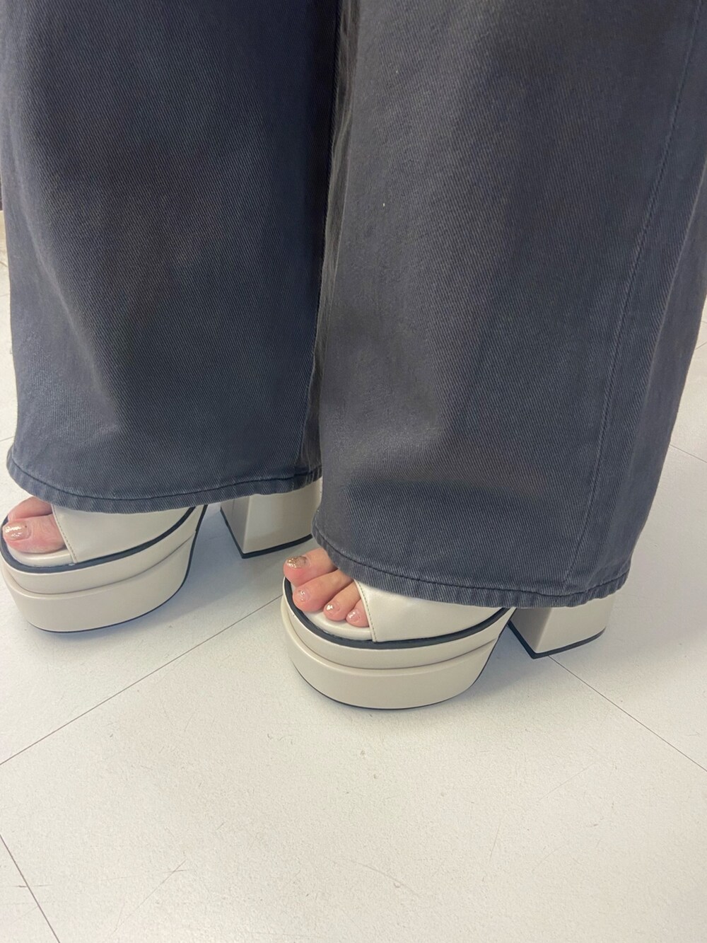 ブラック系のTシャツ/カットソー、ブラック系のデニムパンツ、ホワイト系のサンダルを着用したレディースの春コーディネートの6枚目の写真