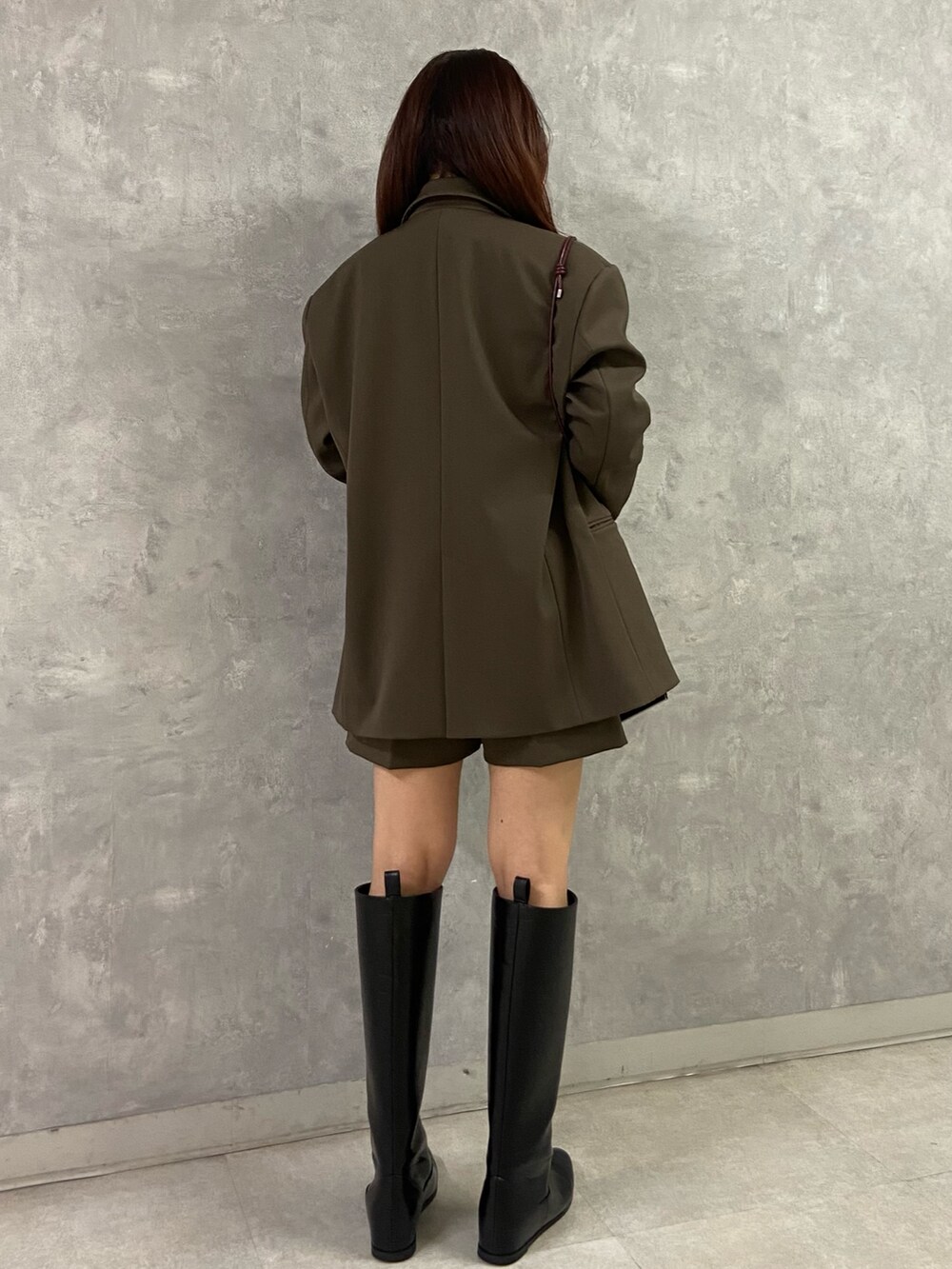 ブラウン系のテーラードジャケット、ブラック系のブーツ、レッド系のショルダーバッグを着用したレディースの秋コーディネートの3枚目の写真