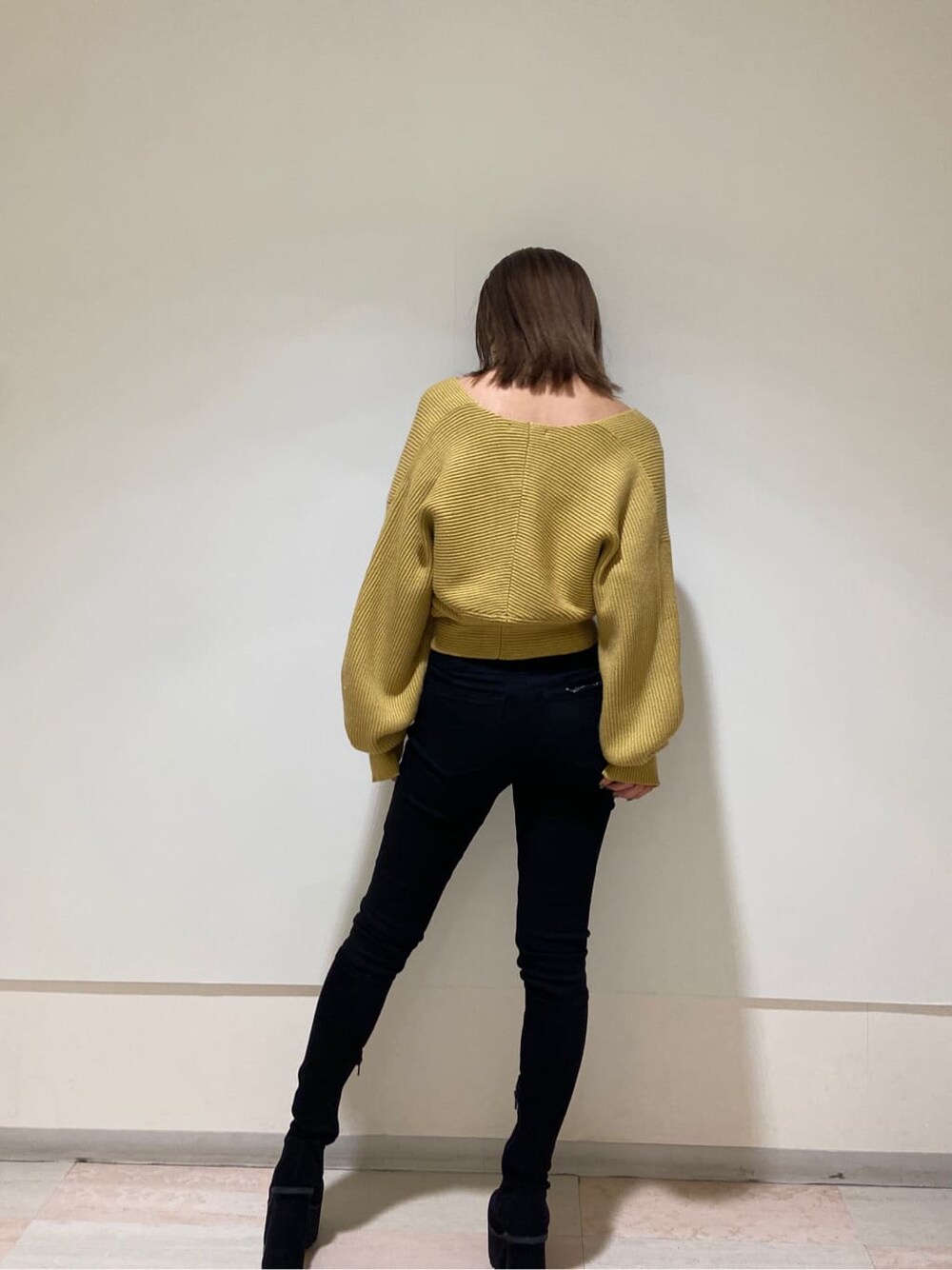 ブラック系のデニムパンツ、ブラック系のブーツ、イエロー系のニット/セーターを着用したレディースの冬コーディネートの2枚目の写真