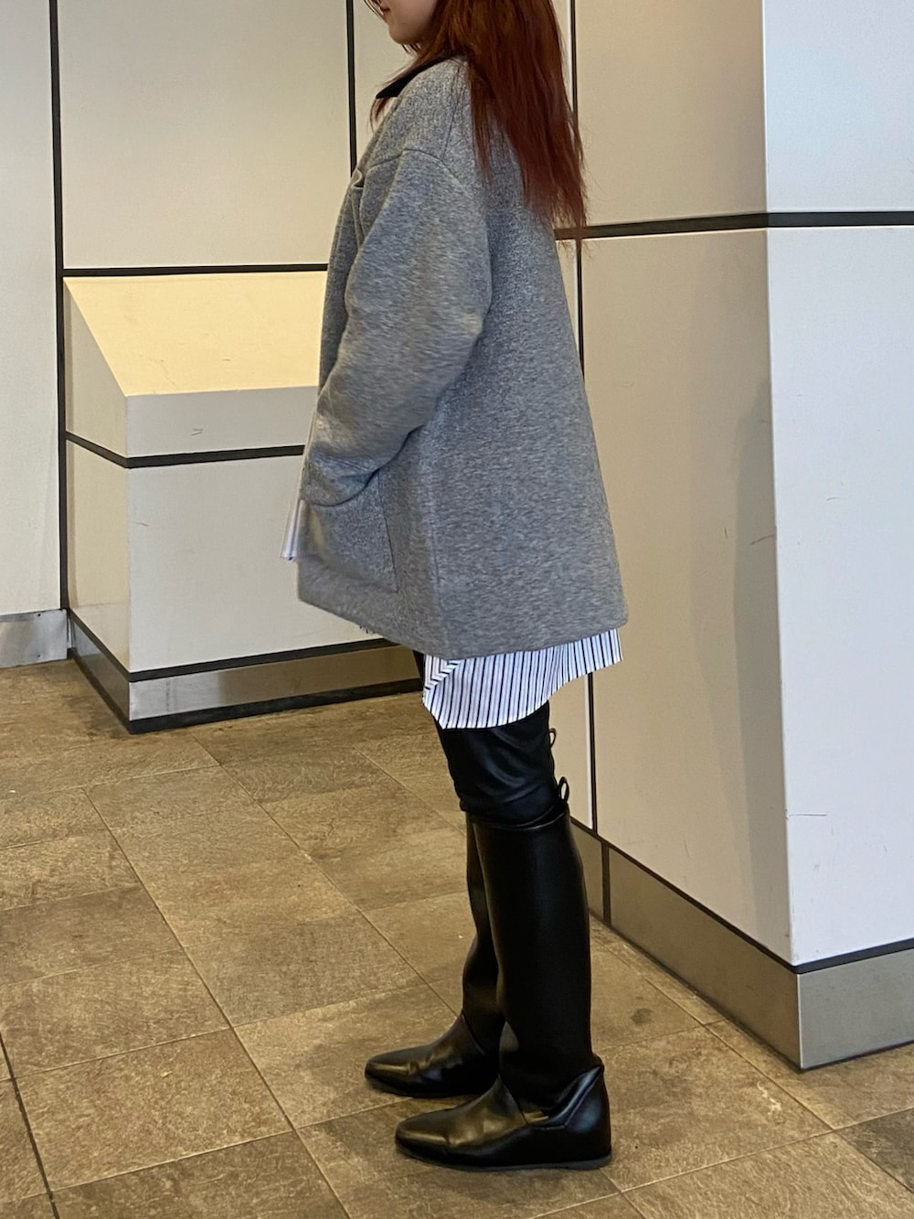 グレー系のブルゾン、ブラック系のブーツ、グレー系のニット/セーターを着用したレディースの秋コーディネートの2枚目の写真