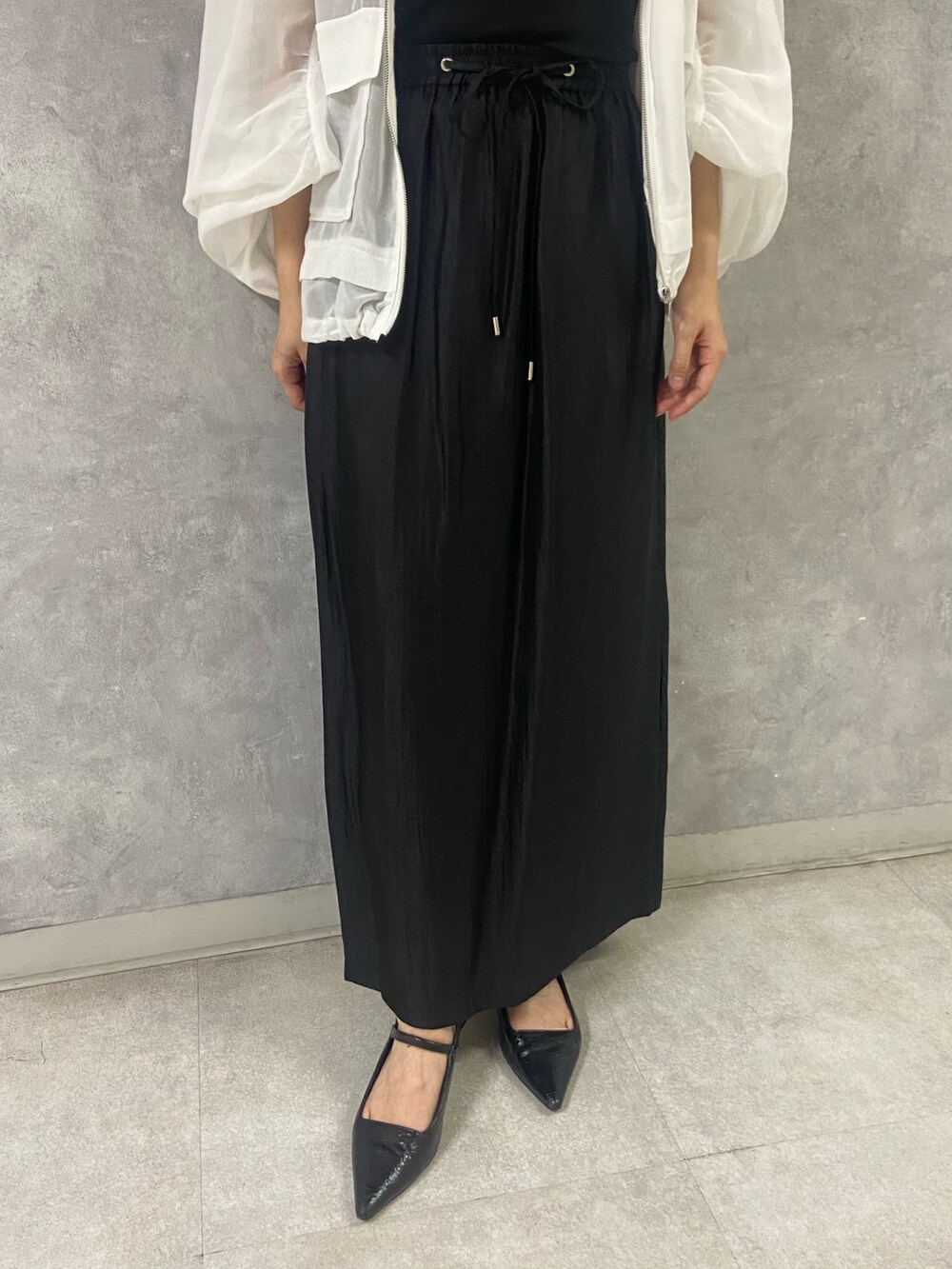 ホワイト系のブルゾン、ブラック系のタンクトップ、ブラック系のスカートを着用したレディースの春コーディネートの5枚目の写真