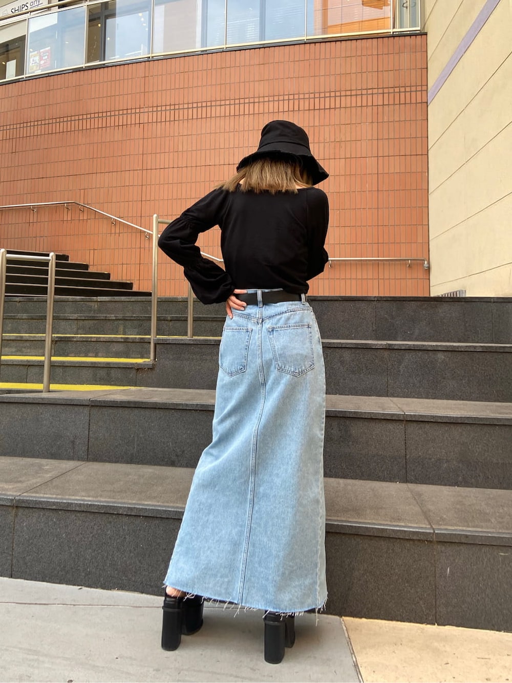 ブルー系のスカート、ブラック系のTシャツ/カットソー、ブラック系のサンダルを着用したレディースの春コーディネートの3枚目の写真