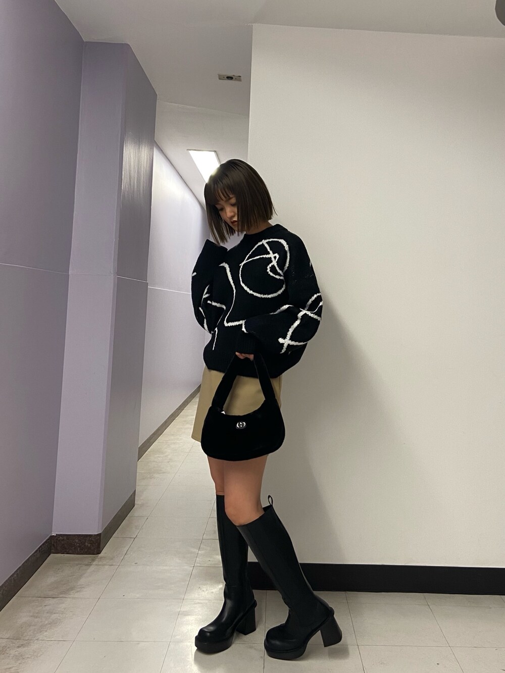 ブラック系のニット/セーター、ベージュ系のスカート、ブラック系のブーツを着用したレディースの秋コーディネートの2枚目の写真