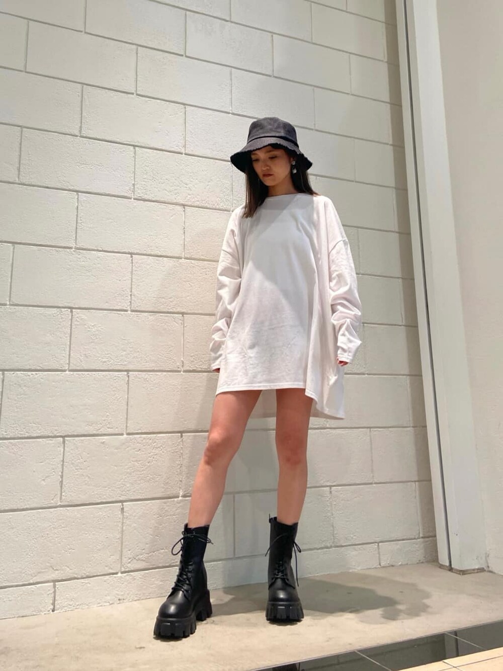 ブラック系のブーツ、ホワイト系のTシャツ/カットソー、ブラック系のハットを着用したレディースの冬コーディネートの2枚目の写真