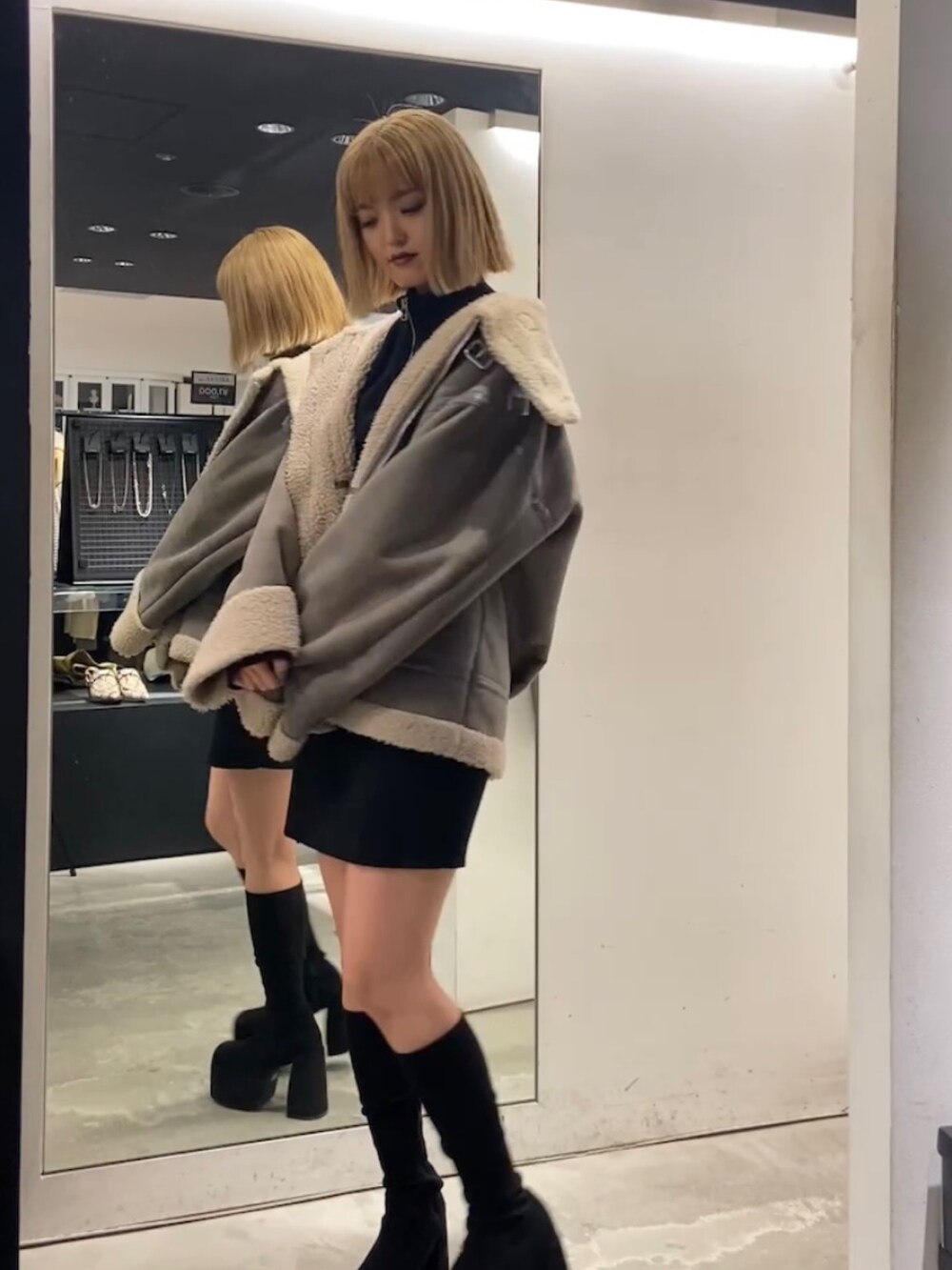 グレー系のブルゾン、ブラック系のワンピース、ブラック系のブーツを着用したレディースの冬コーディネートの4枚目の写真