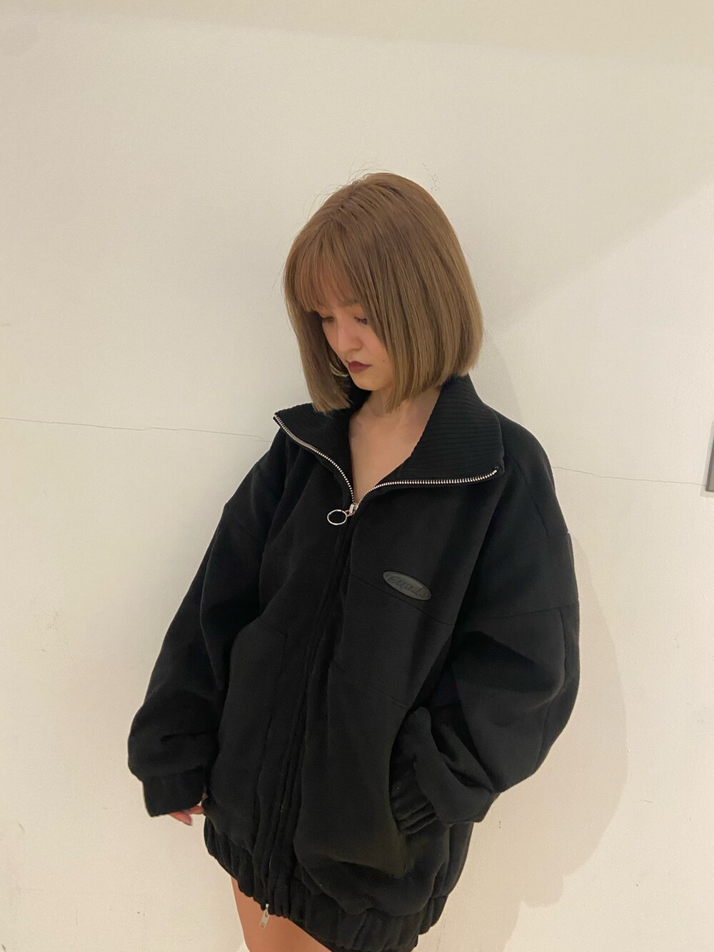 ブラック系のブルゾン、ブラック系のスカート、ブラック系のブーツを着用したレディースの秋コーディネートの4枚目の写真