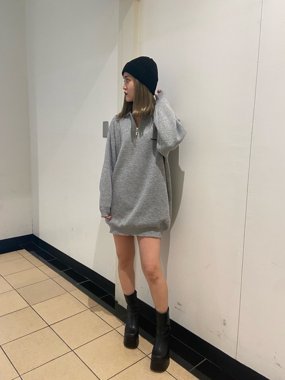 グレー系のワンピース、ブラック系のブーツ、ブラック系のニットキャップ/ビーニーを着用したレディースの秋コーディネートの2枚目の写真