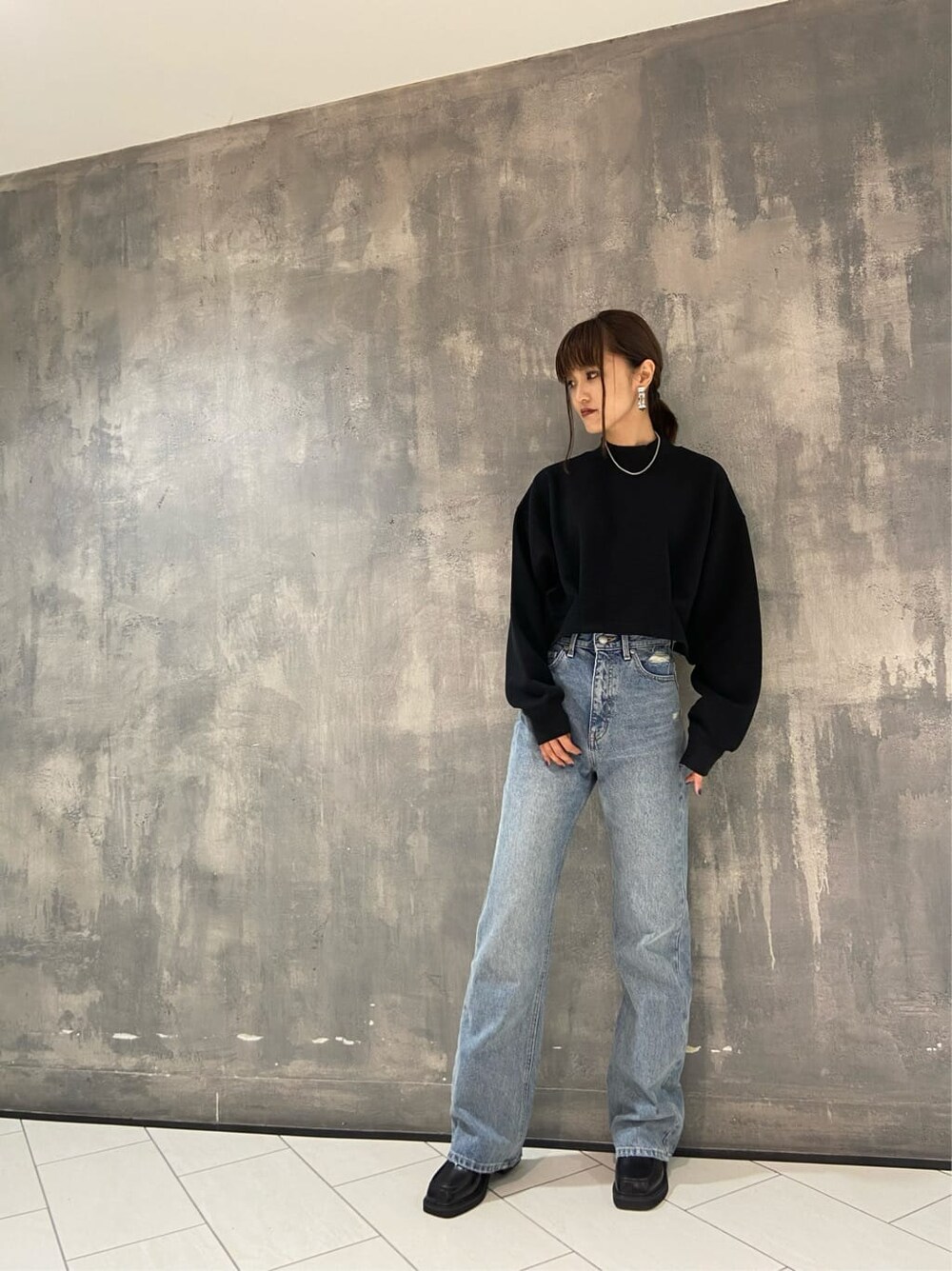 ブラック系のブーツ、ブラック系のTシャツ/カットソー、ブルー系のデニムパンツを着用したレディースの秋コーディネートの6枚目の写真