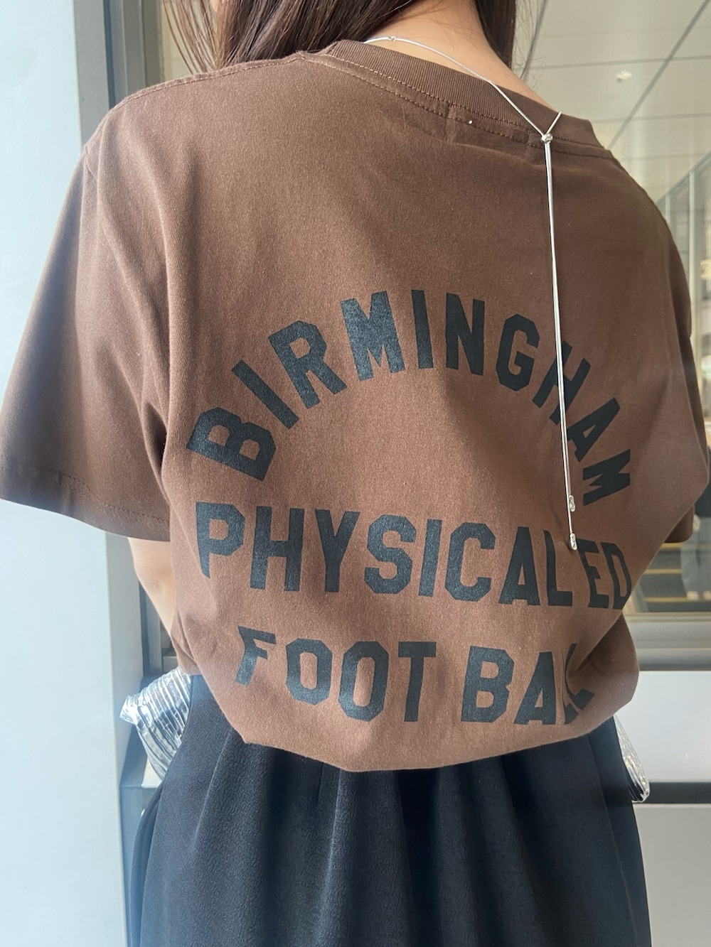 ブラック系のスカート、ブラウン系のTシャツ/カットソー、ホワイト系のサンダルを着用したレディースの春コーディネートの5枚目の写真