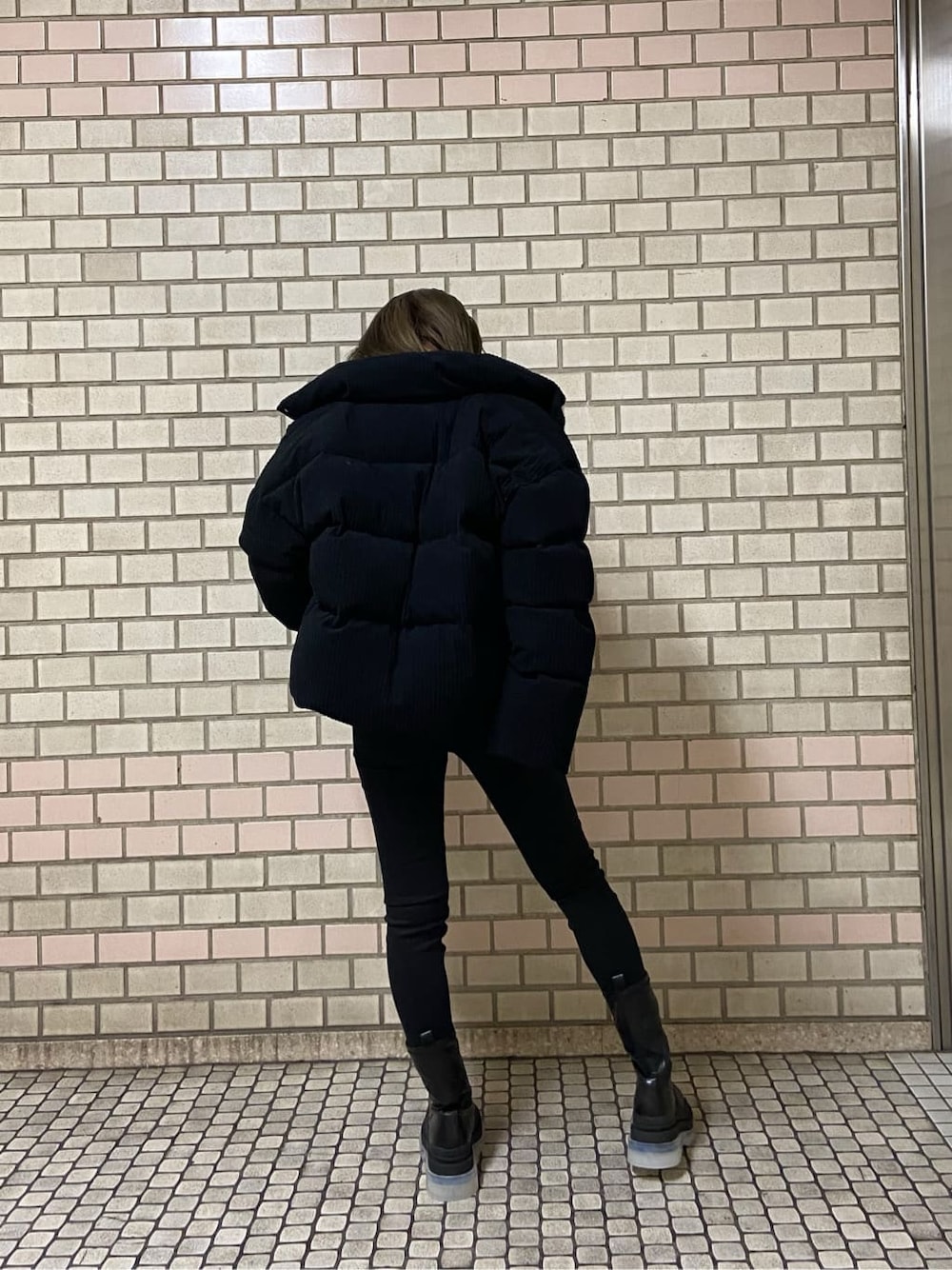 ブラック系のブーツ、ブラック系のニット/セーター、ブラック系のダウンジャケット/コートを着用したレディースの冬コーディネートの2枚目の写真