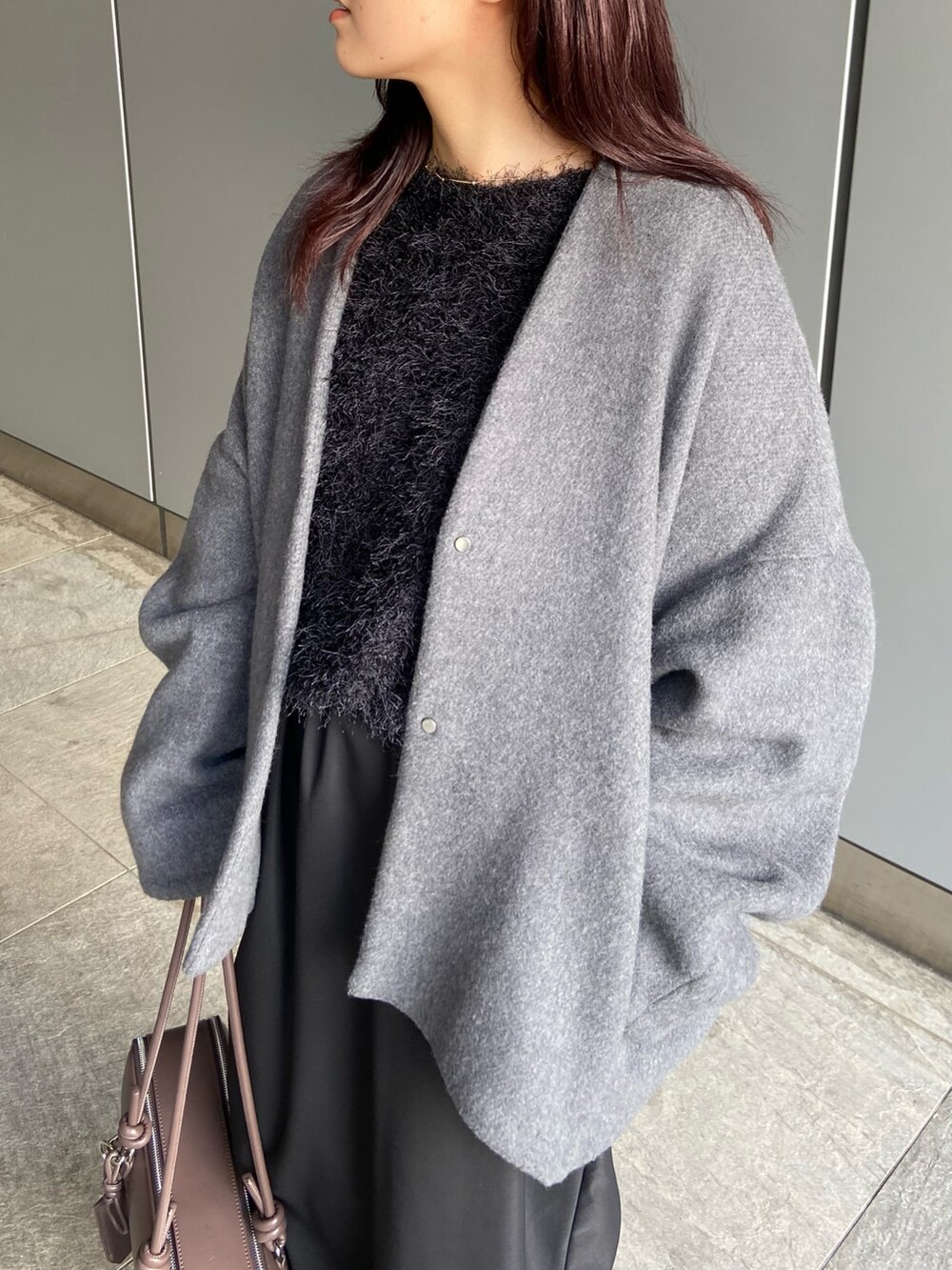 ブラック系のスカート、ブラウン系のボストンバッグ、ブラック系のブーツを着用したレディースの冬コーディネートの4枚目の写真