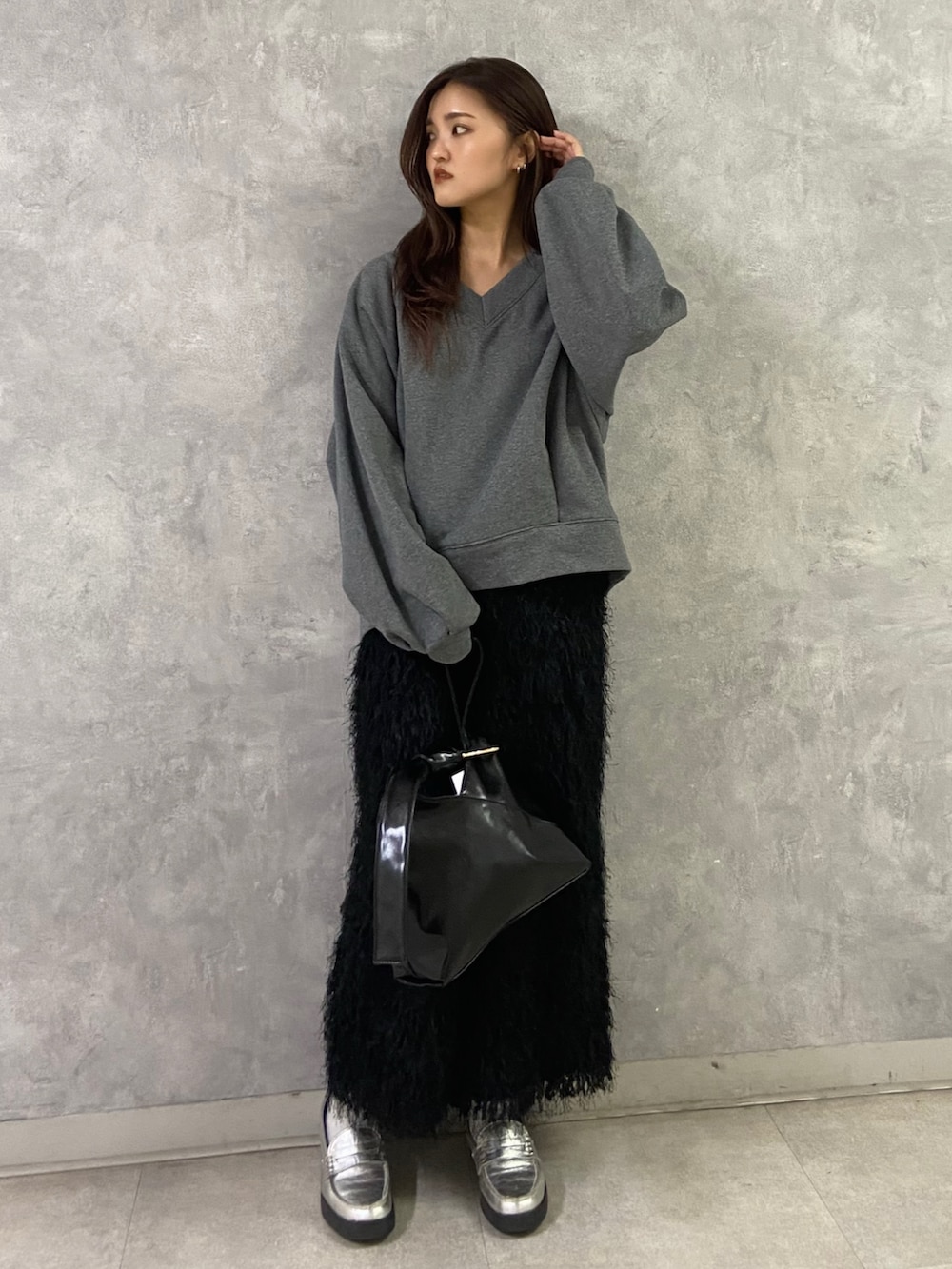 グレー系のTシャツ/カットソー、ブラック系のスカート、シルバー系のローファーを着用したレディースの冬コーディネートの2枚目の写真