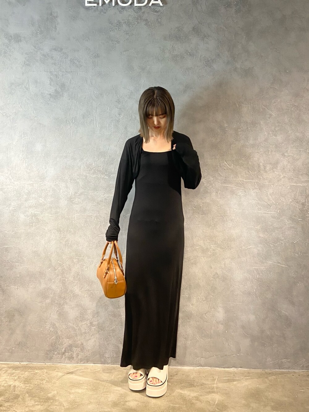 ブラック系のワンピース、ブラック系のハンドバッグ、ホワイト系のサンダルを着用したレディースの春コーディネートの3枚目の写真