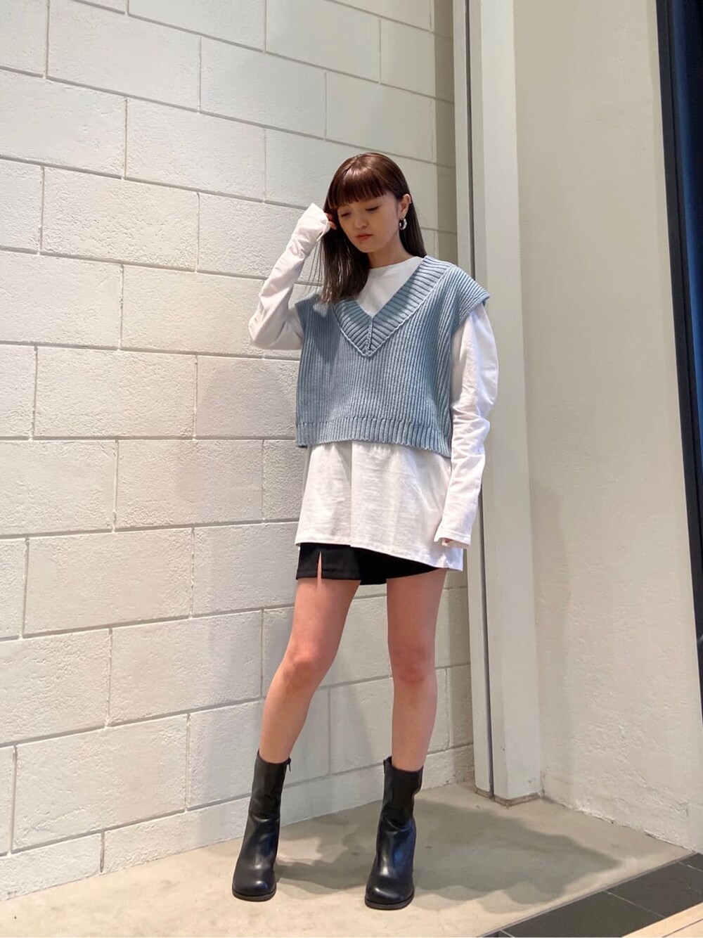 ブラック系のスカート、ブラック系のブーツ、ブルー系のベストを着用したレディースの春コーディネートの6枚目の写真