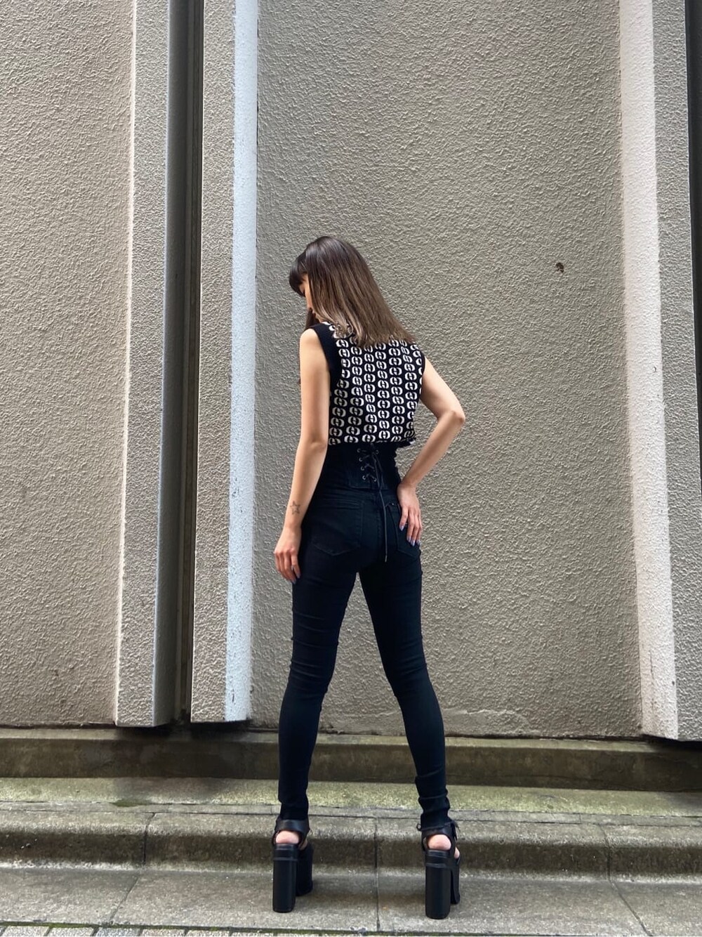 ブラック系のサンダル、その他のタンクトップ、ブラック系のデニムパンツを着用したレディースの春コーディネートの3枚目の写真