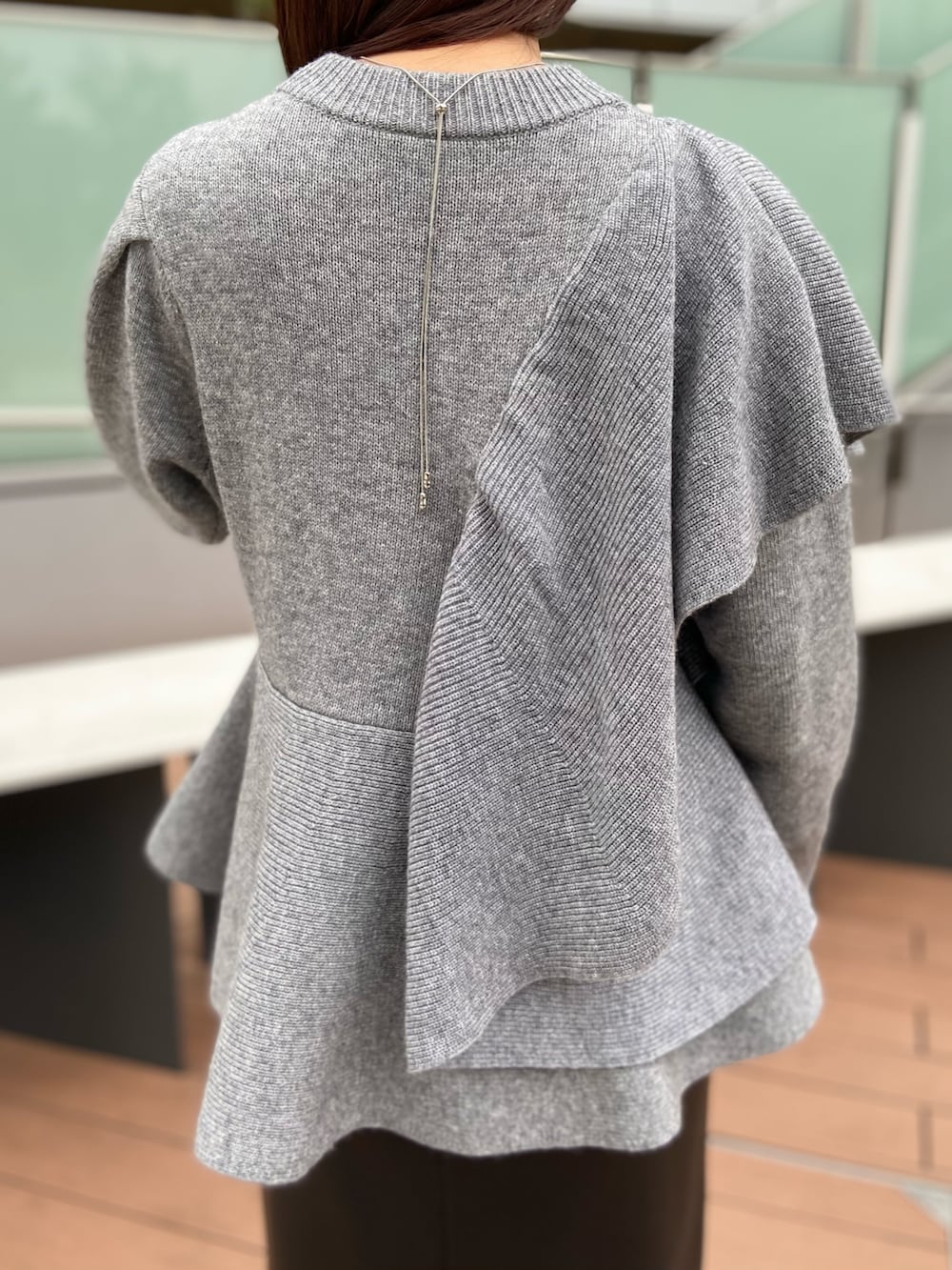 グレー系のニット/セーター、ブラック系のスカート、ブラック系のブーツを着用したレディースの秋コーディネートの5枚目の写真