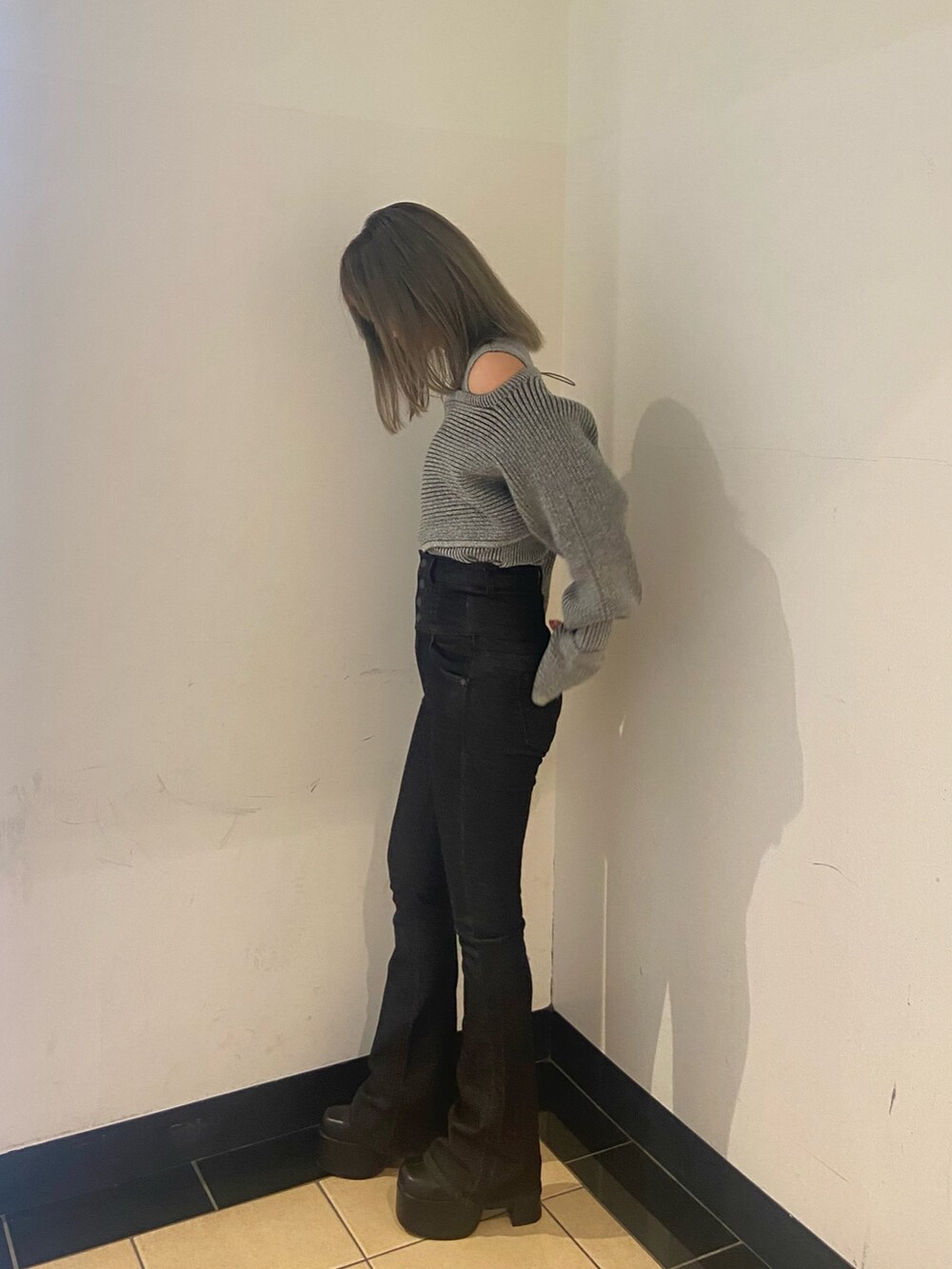 グレー系のニット/セーター、ブラック系のデニムパンツ、ブラック系のブーツを着用したレディースの秋コーディネートの2枚目の写真