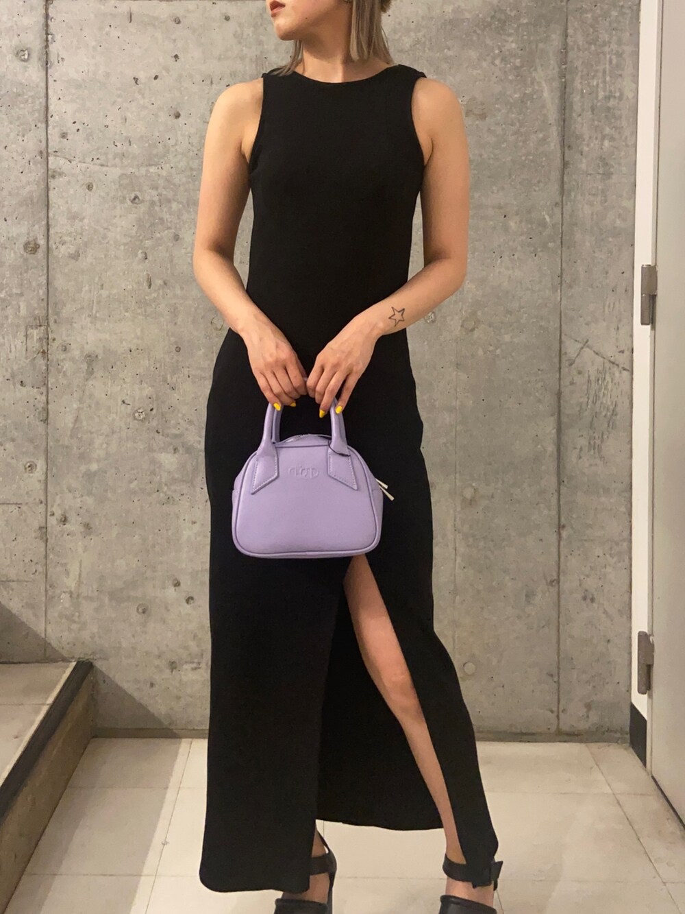 ブラック系のワンピース、パープル系のハンドバッグ、ブラック系のサンダルを着用したレディースの春コーディネートの4枚目の写真