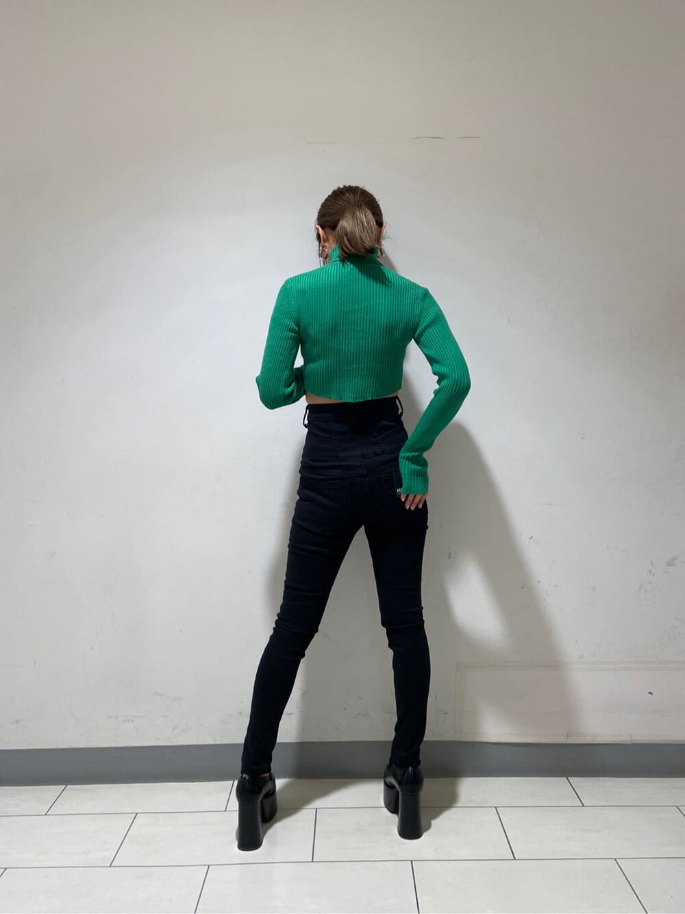 ブラック系のローファー、グリーン系のニット/セーター、ブラック系のデニムパンツを着用したレディースの冬コーディネートの2枚目の写真