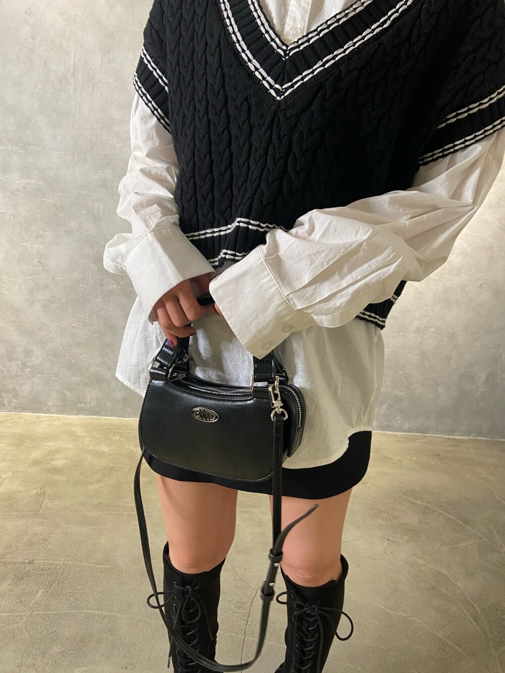 ブラック系のベスト、ホワイト系のシャツ/ブラウス、ブラック系のブーツを着用したレディースの冬コーディネートの6枚目の写真