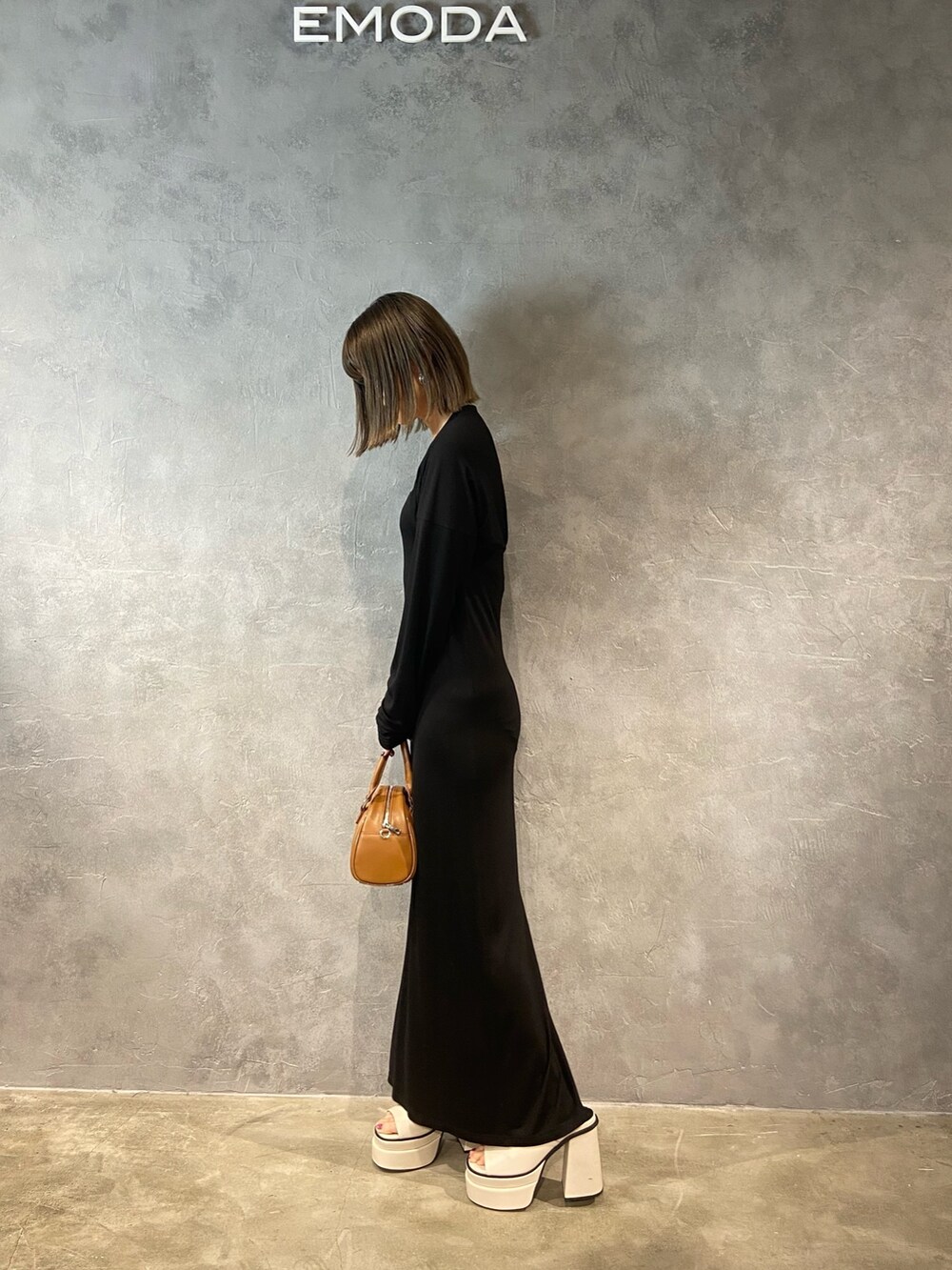 ブラック系のワンピース、ブラック系のハンドバッグ、ホワイト系のサンダルを着用したレディースの春コーディネートの4枚目の写真