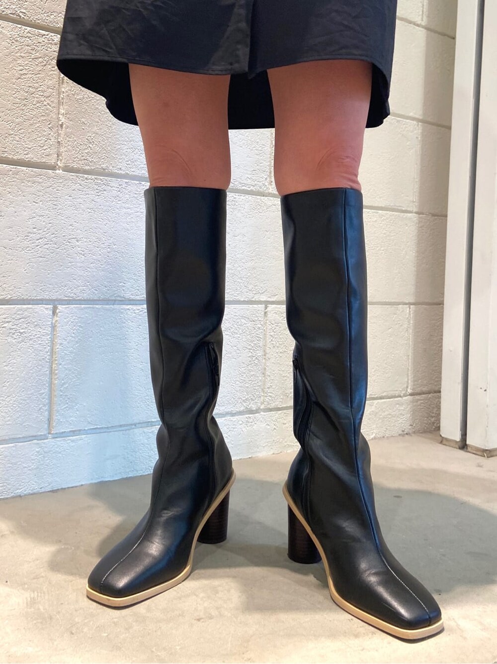 ブラック系のシャツワンピース、ブラック系のブーツ、ブラック系のハンドバッグを着用したレディースの冬コーディネートの6枚目の写真