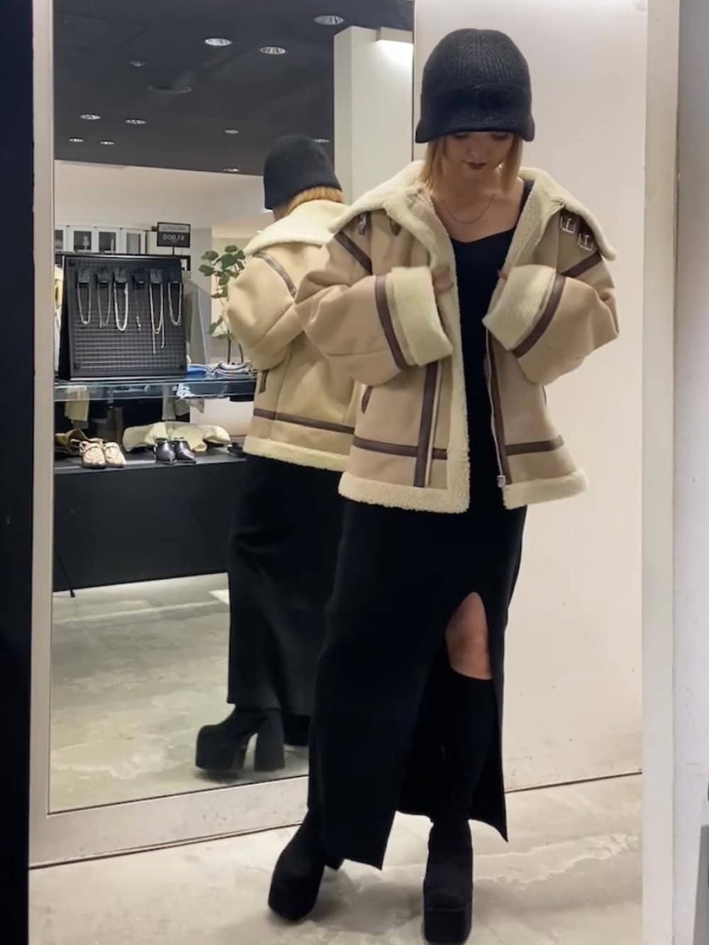 ベージュ系のブルゾン、ブラック系のワンピース、ブラック系のブーツを着用したレディースの冬コーディネートの4枚目の写真