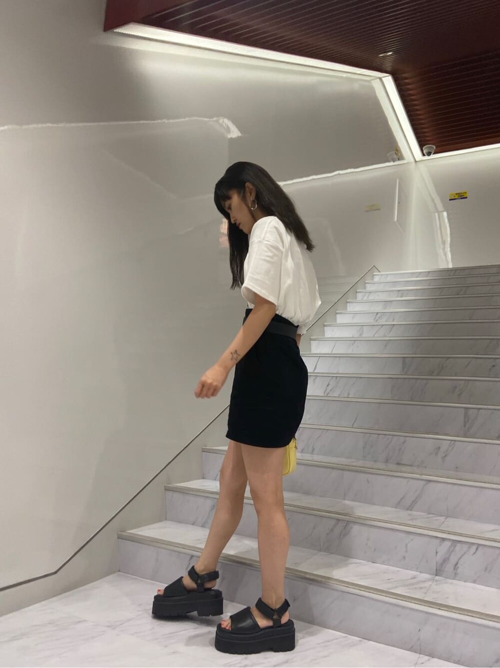 ブラック系のサンダル、ホワイト系のTシャツ/カットソー、ブラック系のスカートを着用したレディースの夏コーディネートの3枚目の写真