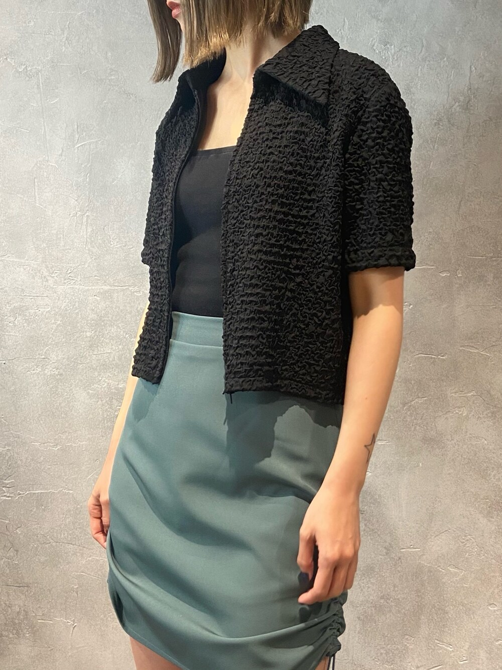 ブラック系のシャツ/ブラウス、グリーン系のスカート、ブラック系のサンダルを着用したレディースの春コーディネートの7枚目の写真