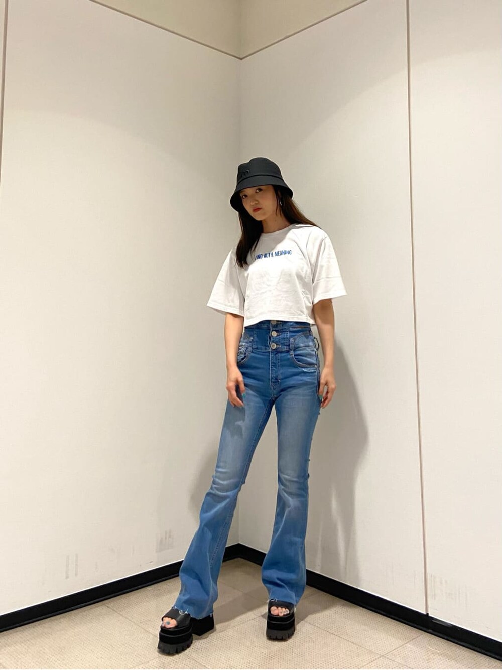 ブルー系のデニムパンツ、ブラック系のサンダル、ホワイト系のTシャツ/カットソーを着用したレディースの夏コーディネートの2枚目の写真