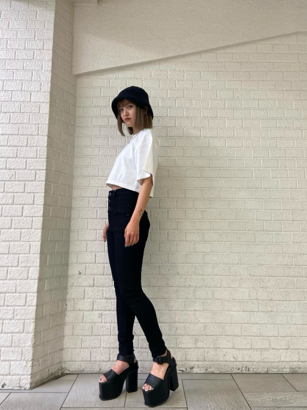 ブラック系のデニムパンツ、ブラック系のサンダル、ホワイト系のTシャツ/カットソーを着用したレディースの夏コーディネートの2枚目の写真