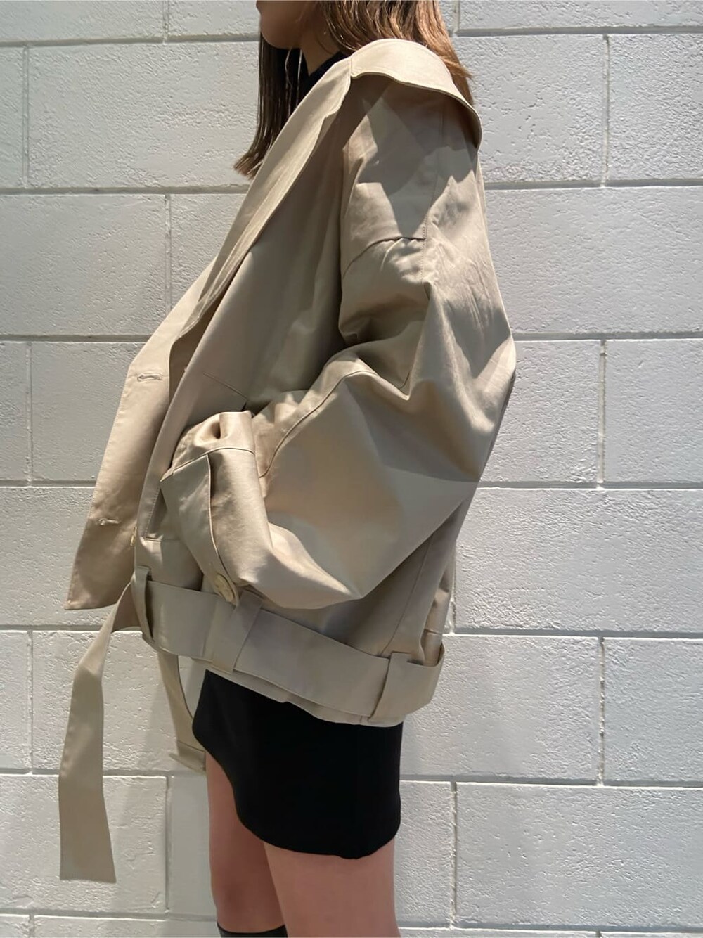 ブラック系のワンピース、ベージュ系のトレンチコート、ブラック系のブーツを着用したレディースの冬コーディネートの3枚目の写真