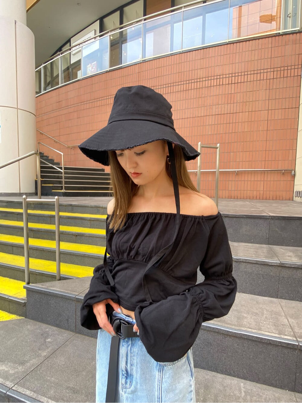 ブルー系のスカート、ブラック系のTシャツ/カットソー、ブラック系のサンダルを着用したレディースの春コーディネートの4枚目の写真