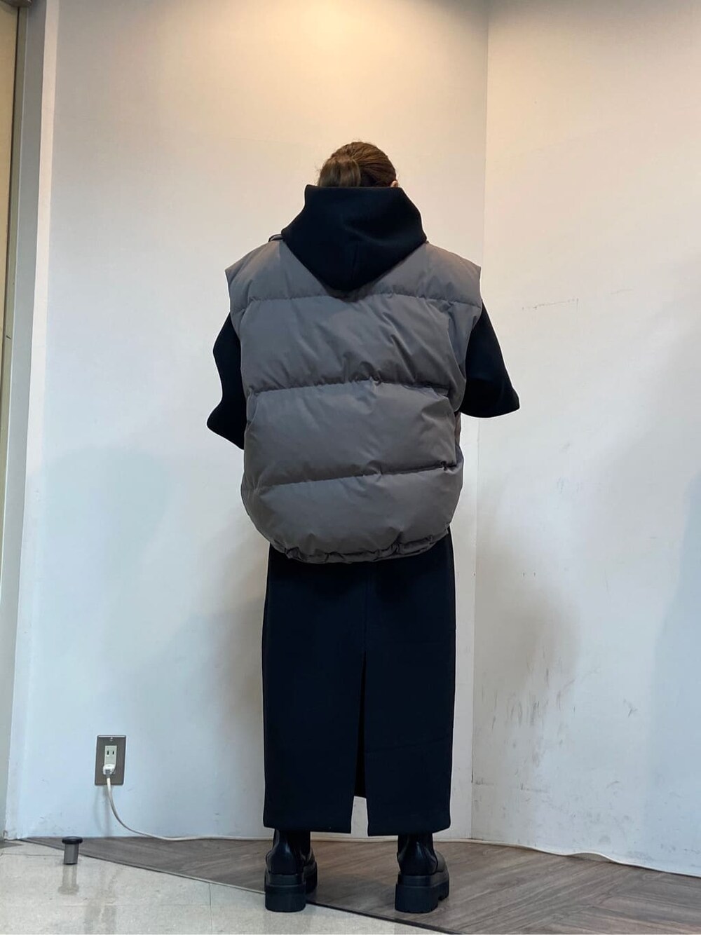 グレー系のダウンベスト、ブラック系のワンピースを着用したレディースの秋コーディネートの6枚目の写真