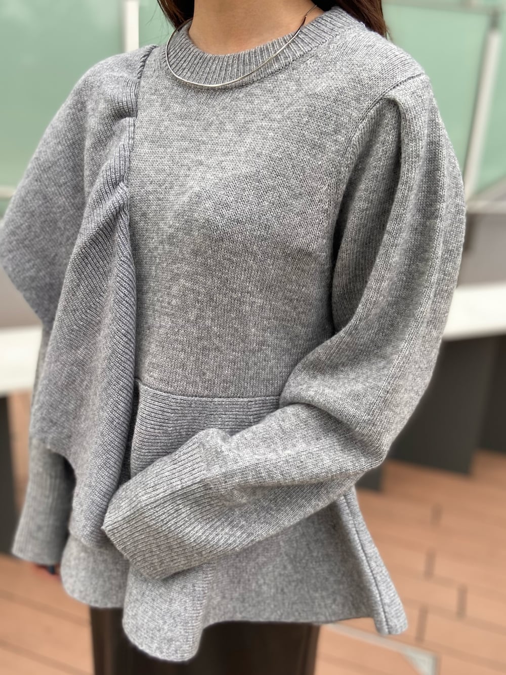 グレー系のニット/セーター、ブラック系のスカート、ブラック系のブーツを着用したレディースの秋コーディネートの4枚目の写真