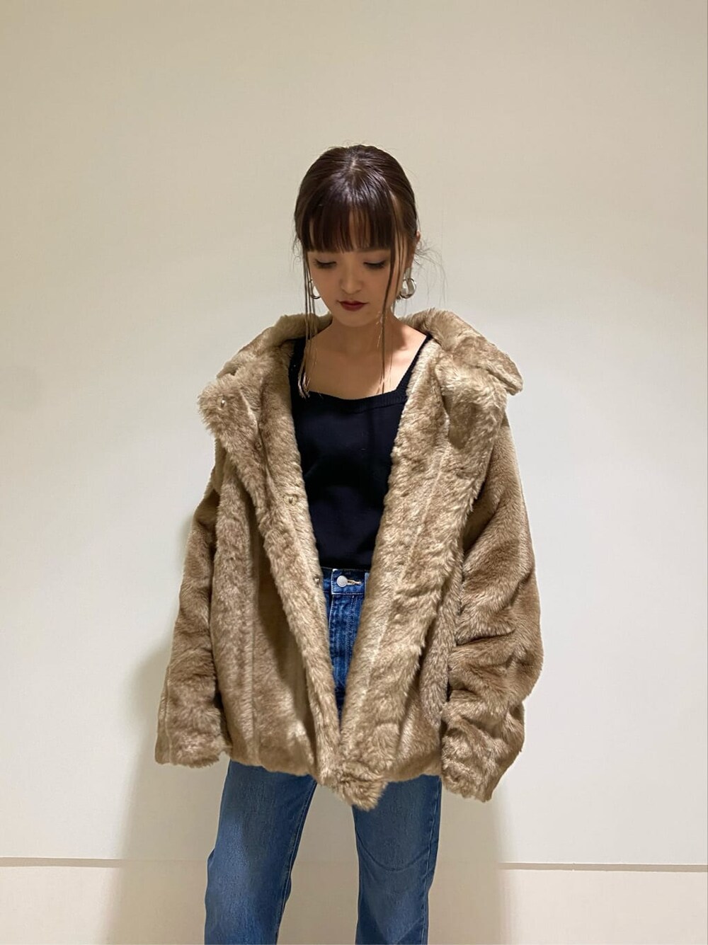 ブルー系のデニムパンツ、ブラック系のブーツ、ベージュ系のその他アウターを着用したレディースの冬コーディネートの2枚目の写真