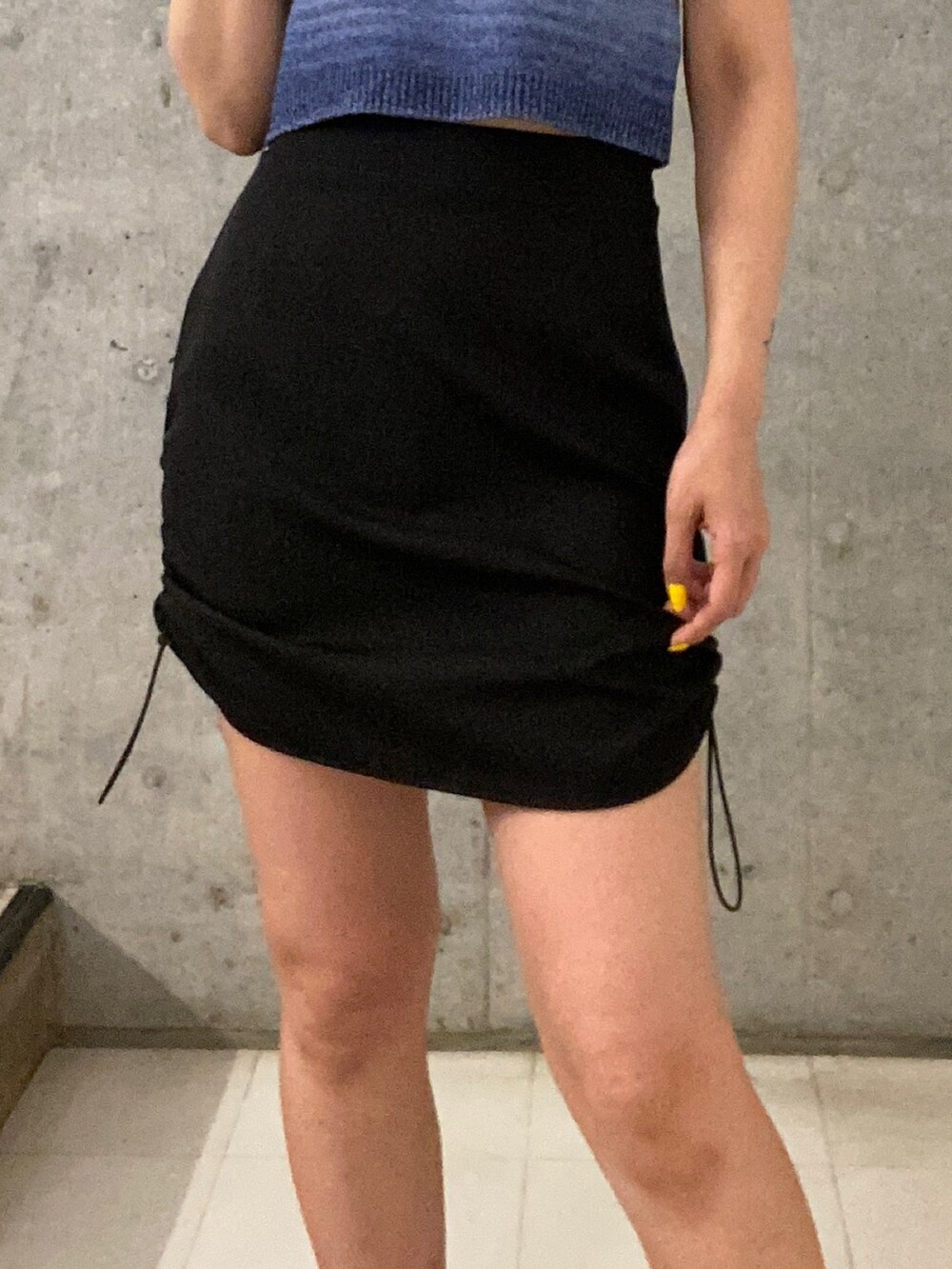 ブルー系のタンクトップ、ブラック系のスカート、ブラック系のサンダルを着用したレディースの春コーディネートの5枚目の写真