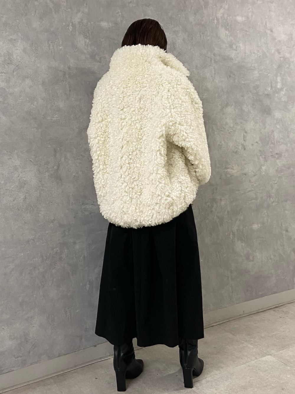 ホワイト系のブルゾン、ブラック系のワンピース、ブラック系のブーツを着用したレディースの冬コーディネートの3枚目の写真