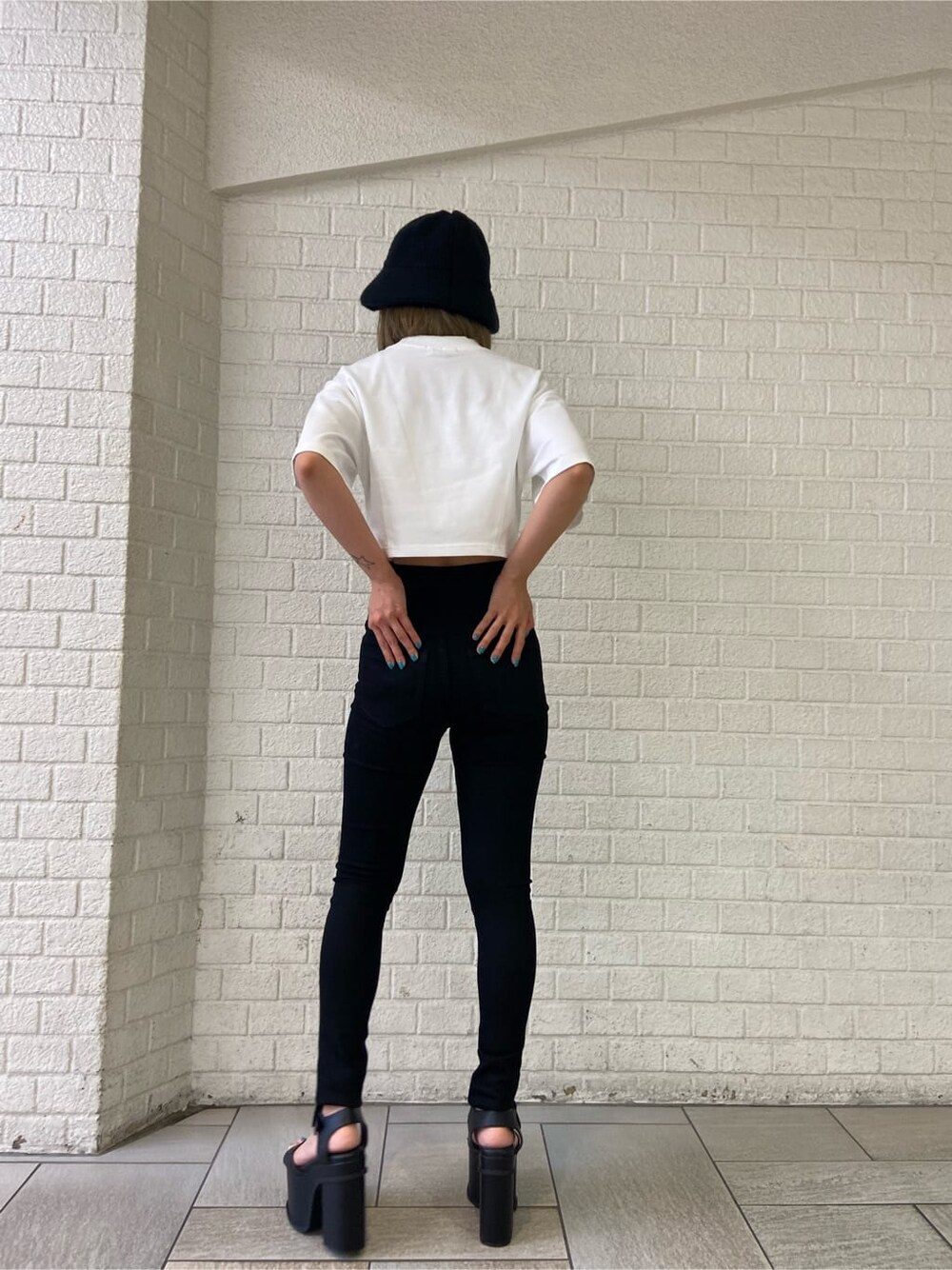 ブラック系のデニムパンツ、ブラック系のサンダル、ホワイト系のTシャツ/カットソーを着用したレディースの夏コーディネートの3枚目の写真