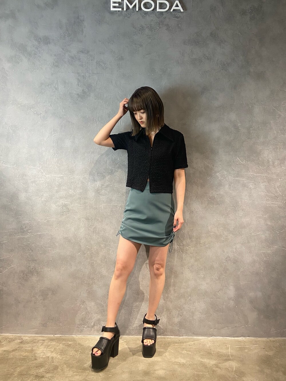 ブラック系のシャツ/ブラウス、グリーン系のスカート、ブラック系のサンダルを着用したレディースの春コーディネートの2枚目の写真