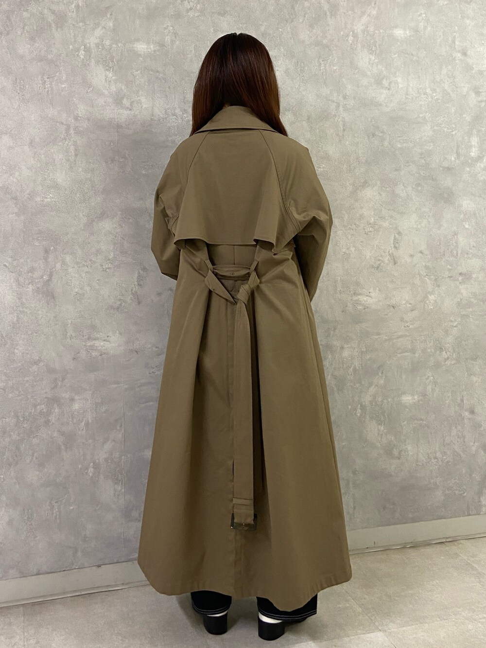 ブラウン系のトレンチコート、ブラック系のニット/セーター、ブルー系のデニムパンツを着用したレディースの秋コーディネートの4枚目の写真