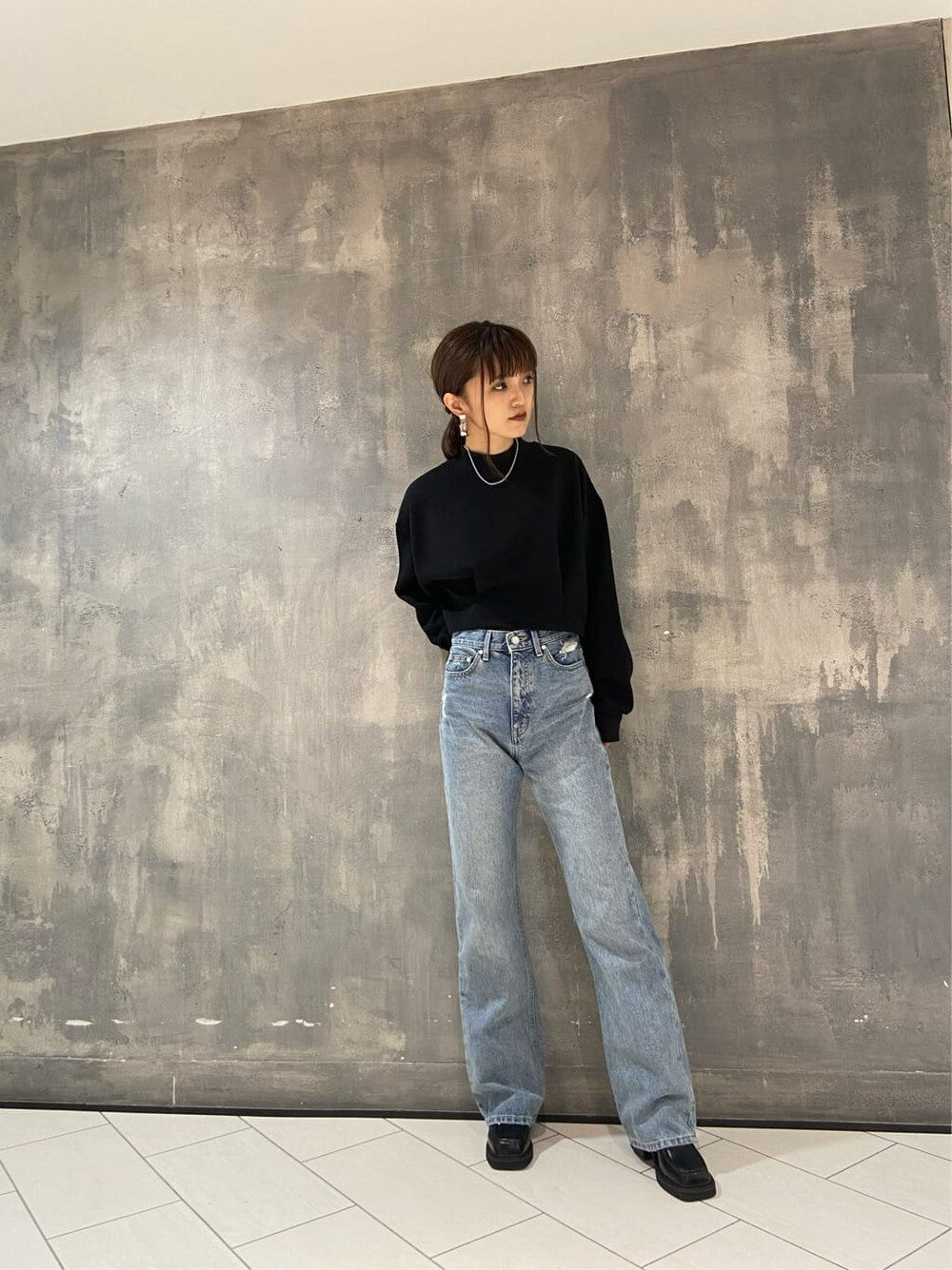 ブラック系のブーツ、ブラック系のTシャツ/カットソー、ブルー系のデニムパンツを着用したレディースの秋コーディネートの2枚目の写真