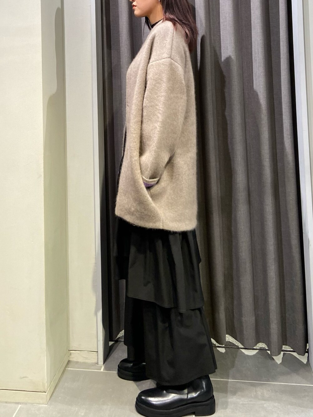 ベージュ系のカーディガン/ボレロ、ブラック系のスカート、ブラック系のブーツを着用したレディースの秋コーディネートの3枚目の写真