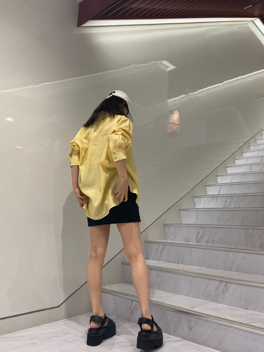 ホワイト系のタンクトップ、ブラック系のサンダル、ブラック系のスカートを着用したレディースの夏コーディネートの3枚目の写真