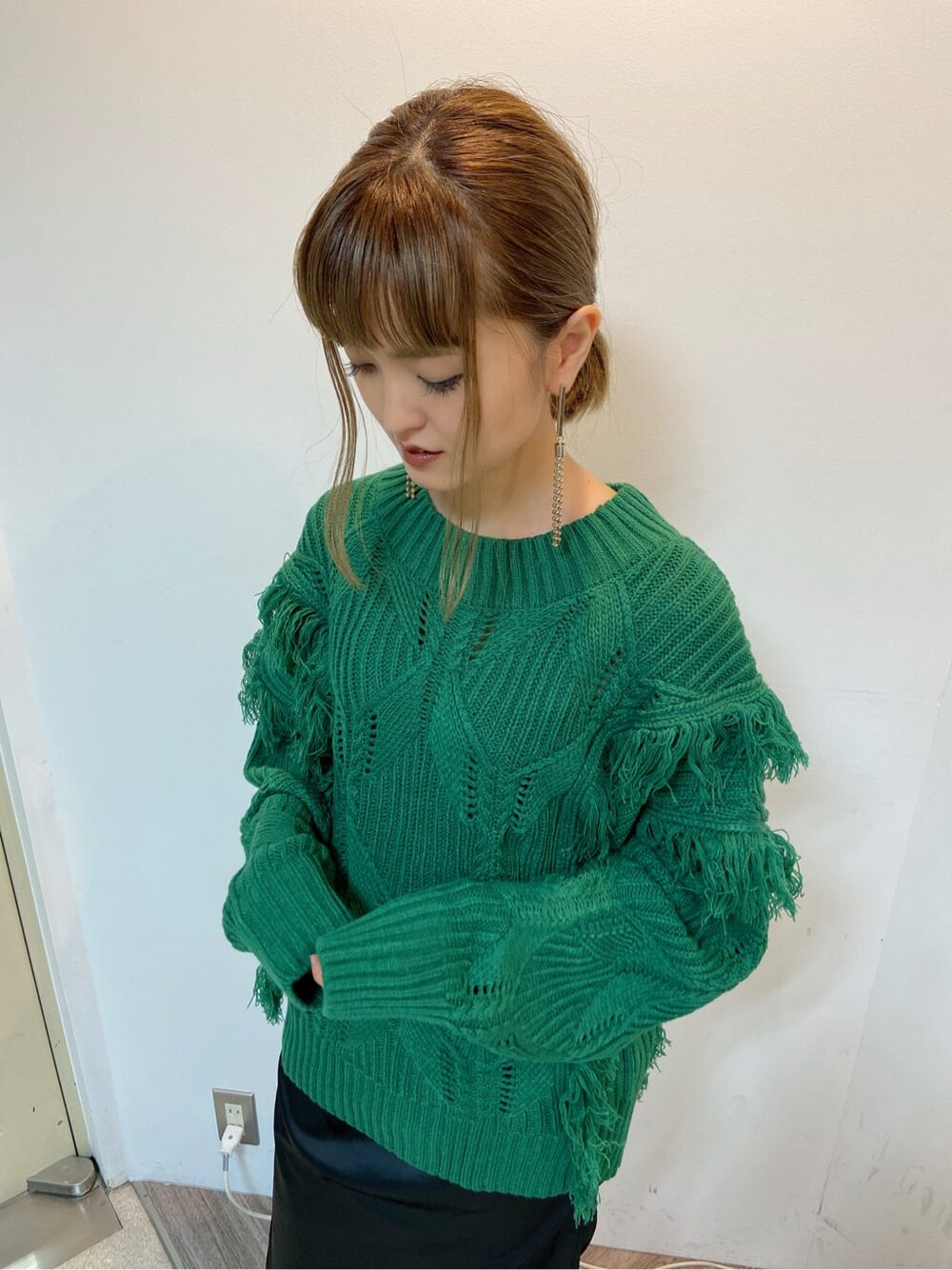 ブラック系のスカート、ブラック系のブーツ、グリーン系のニット/セーターを着用したレディースの秋コーディネートの2枚目の写真